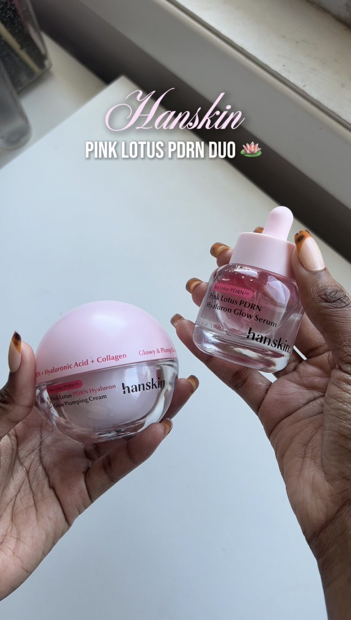 Two hands holding pink jars of skincare products near a window, with text overlay about pink lotus PDRN duo, 20 words