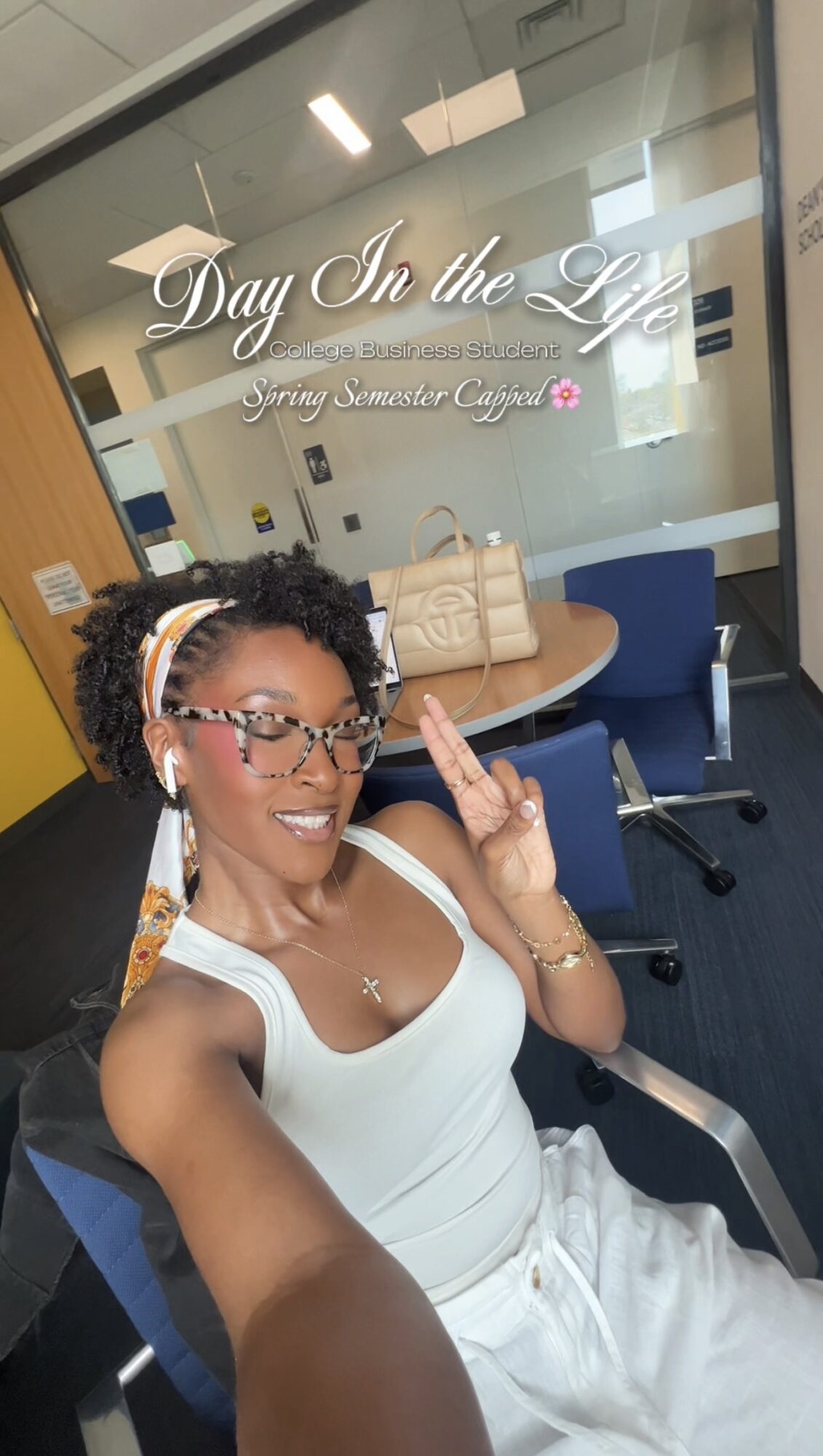 Woman smiling in a white dress taking a selfie in a room with a glass door that reads 'Day In the Life' and 'Gwen Jennifer Cargill'.
