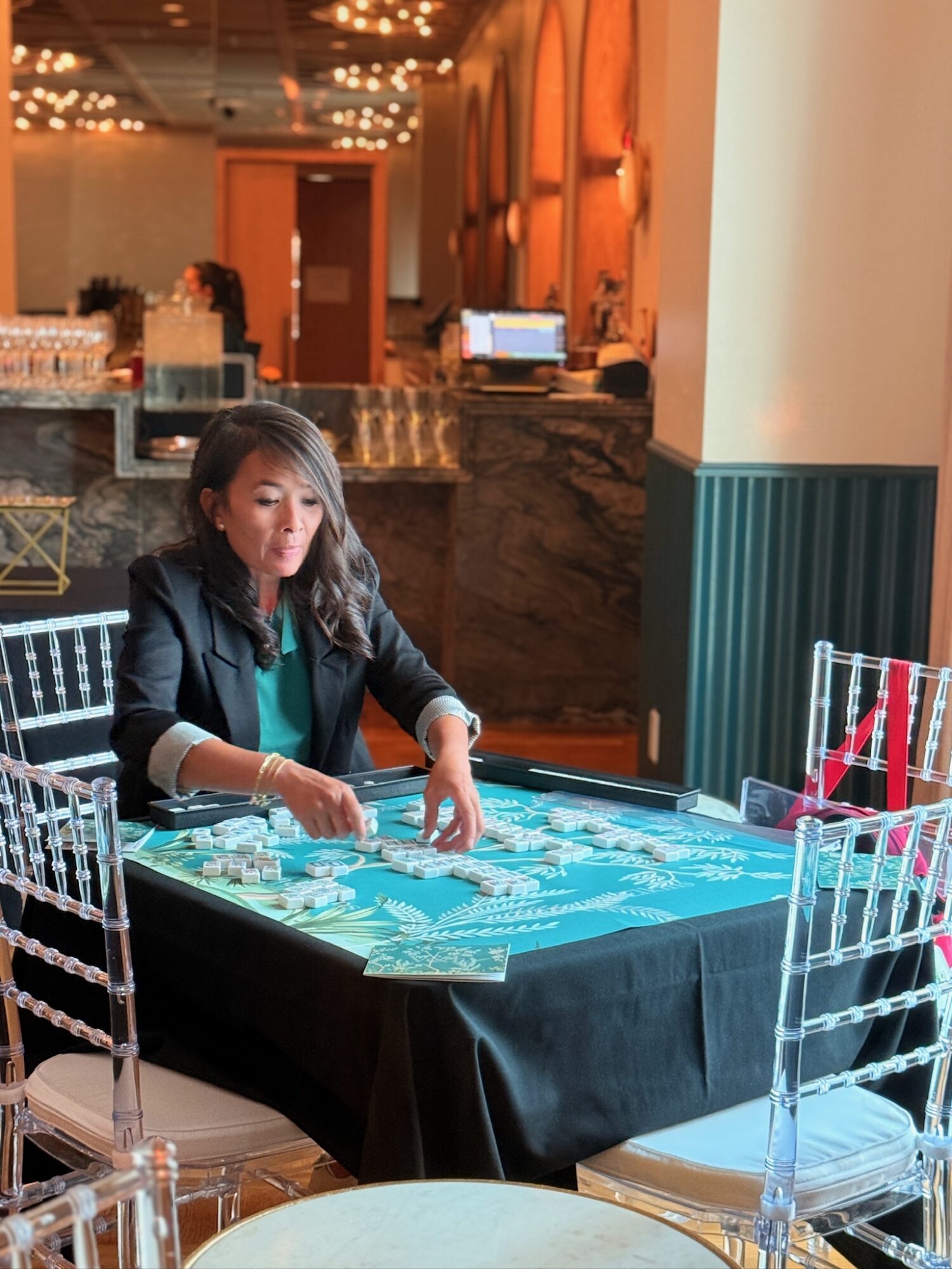 Woman playing a casino game at a table with chips, in a decorated indoor setting.