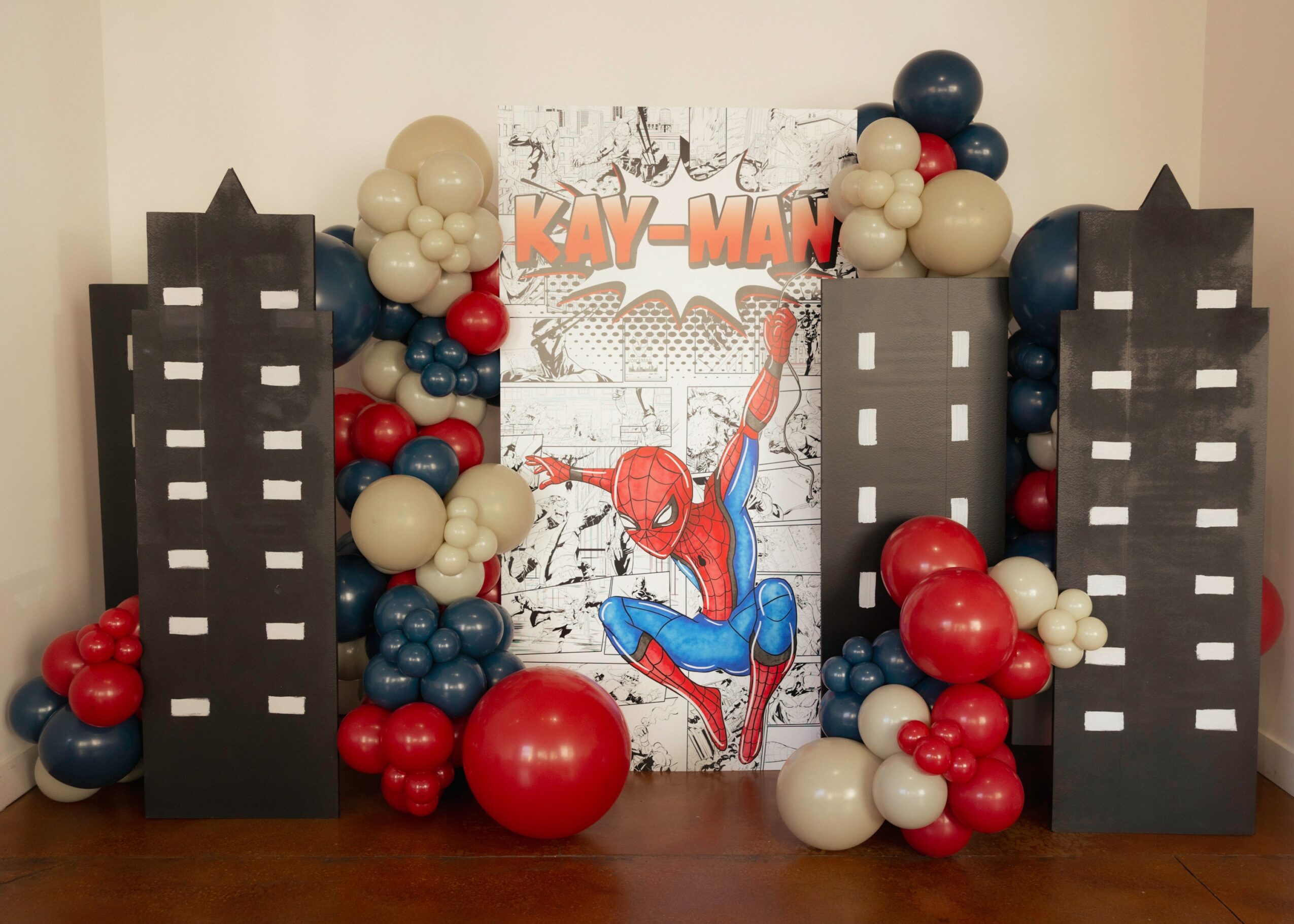 Spider-Man themed decoration with black building cutouts, balloons, and a Spider-Man poster in the center.