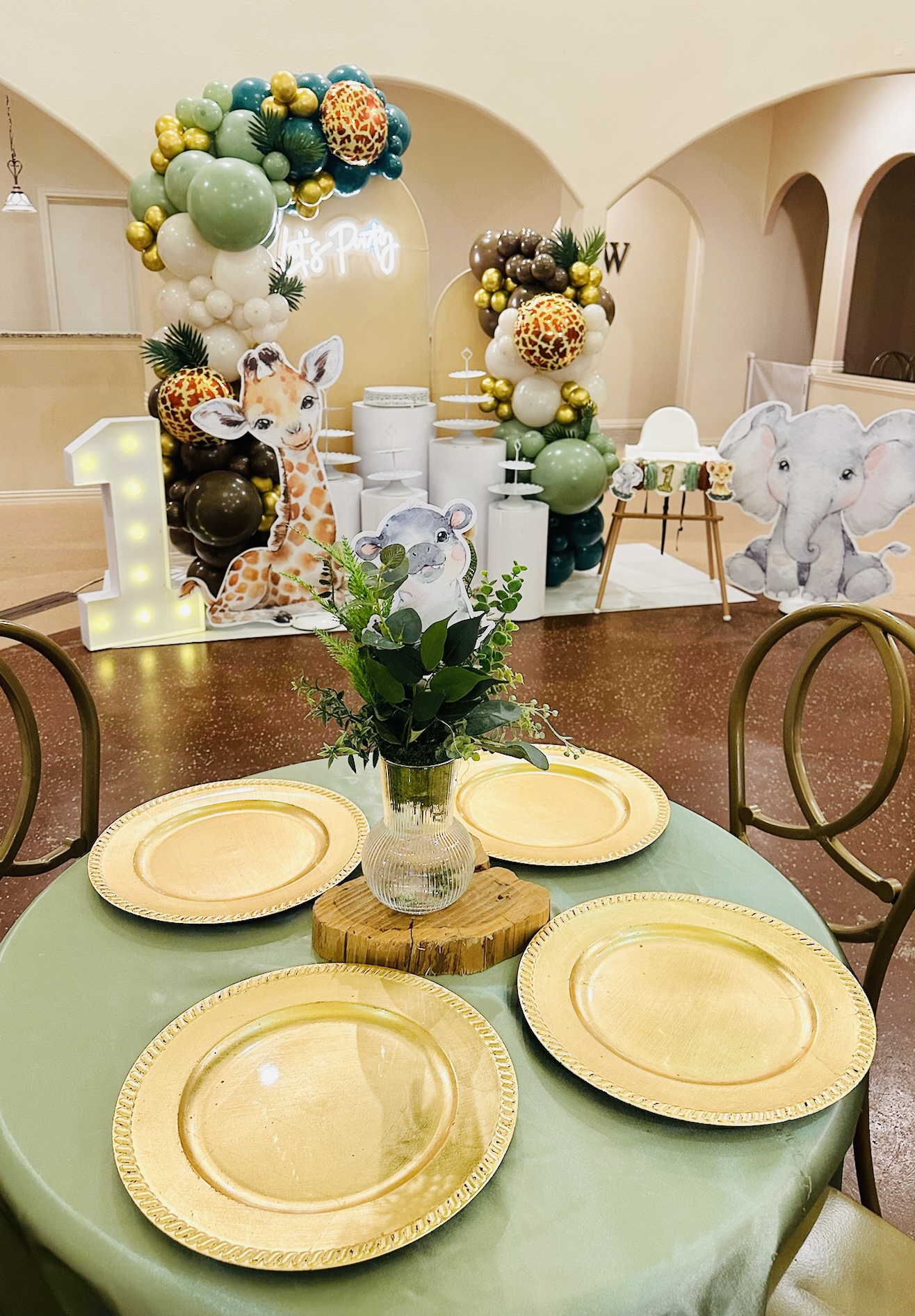 Round table with four yellow plates and a glass vase with green leaves, decorated for a celebration, with a decorated background.
