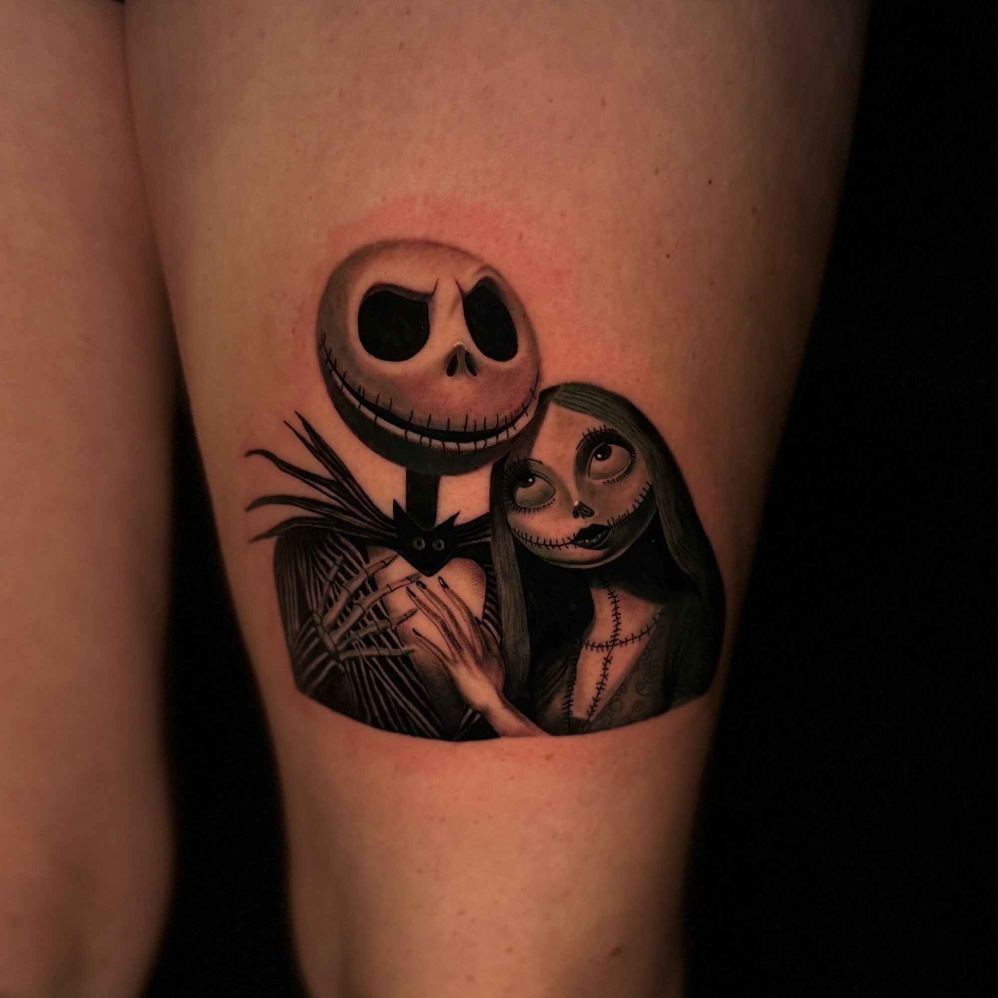 Tattoo of Jack Skellington and Sally from The Nightmare Before Christmas, with Jack smiling and Sally looking at him, on skin.
