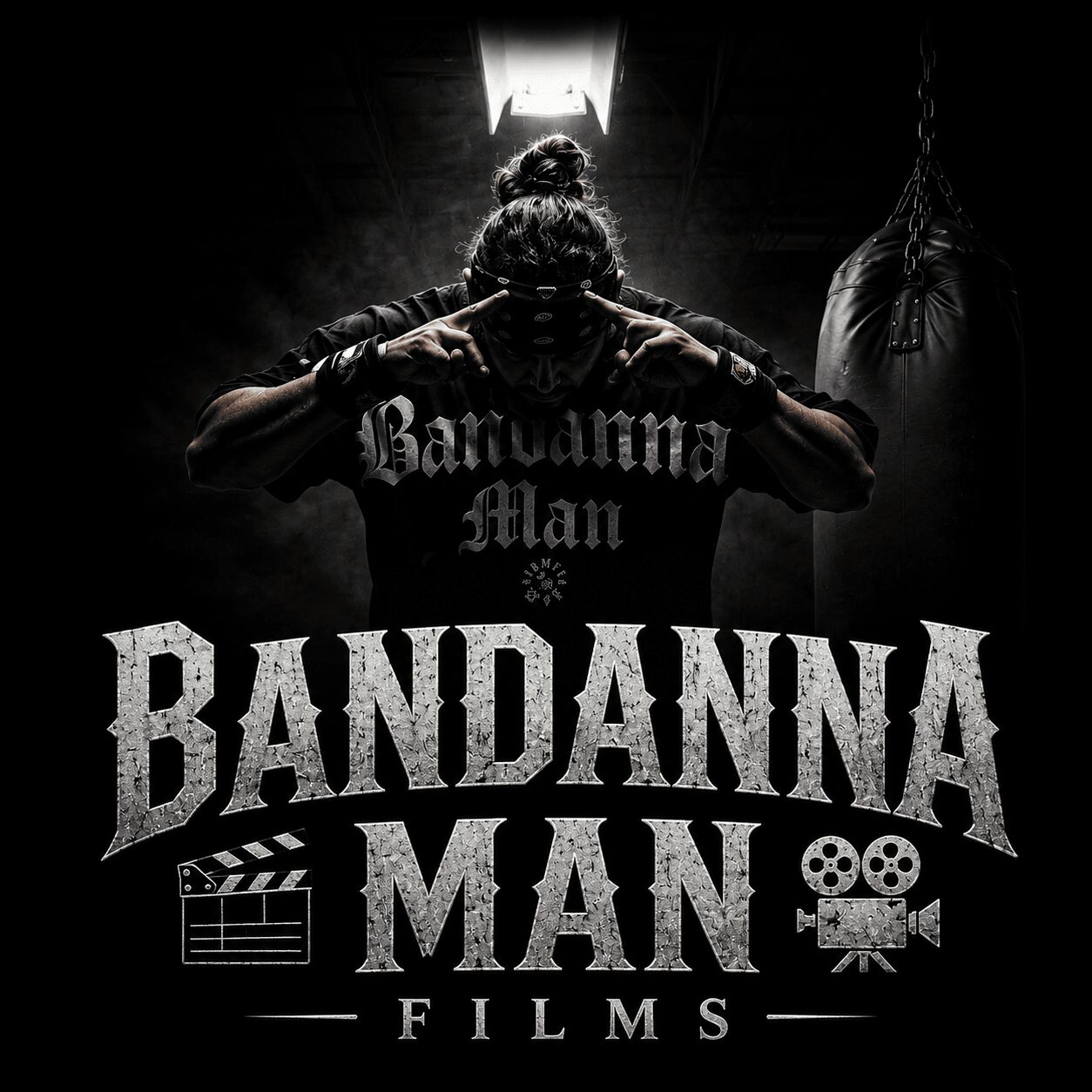 Person with hands near head, wearing a shirt with 'Bandanna Man' text, in dark setting with light above, film icons below.