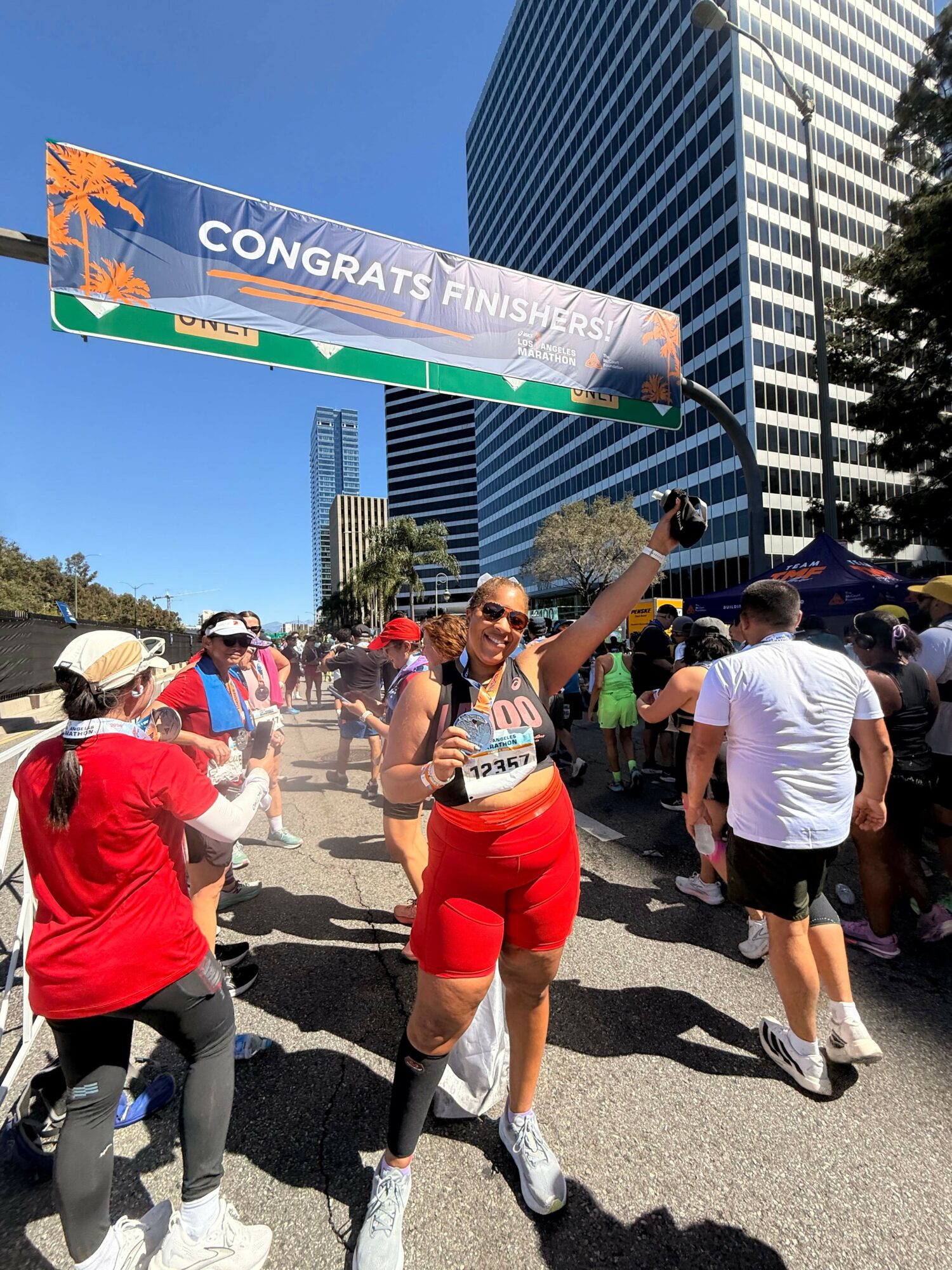 People participating in a marathon or race, with a large banner reading 'CONGRATS FINISHER' in the background, on a city street.