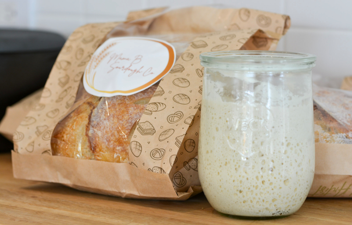 Packaged baked good next to a jar of creamy beverage on a wooden surface.