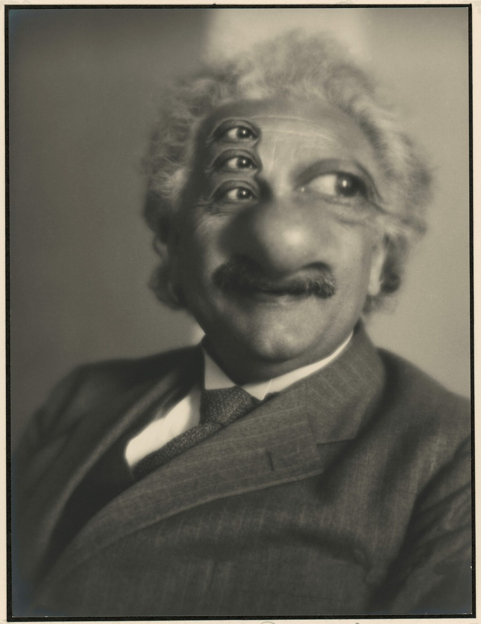 A black and white portrait of a man with a mustache, wearing a suit and bow tie, with a distorted face effect.