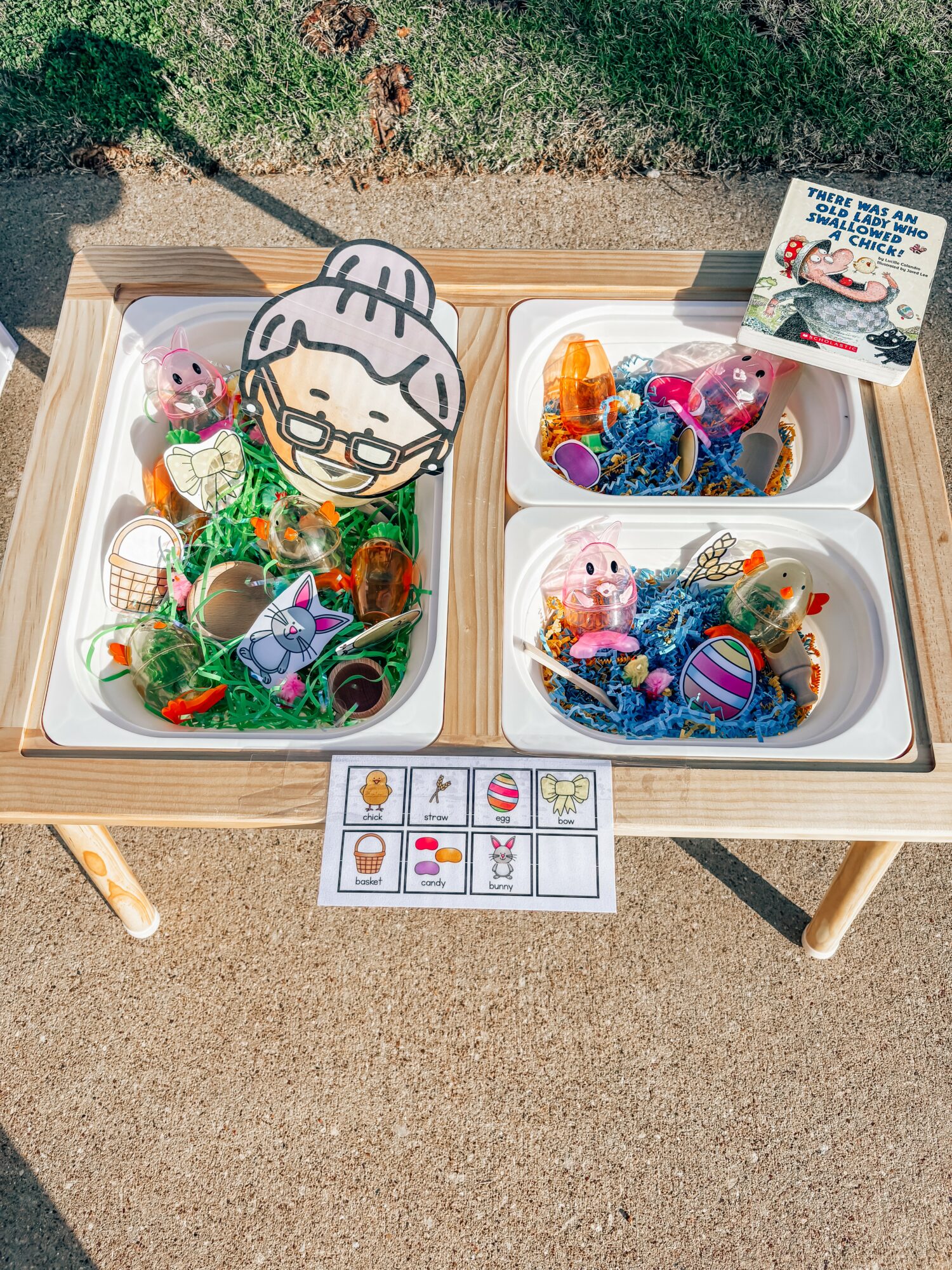 Table with three containers filled with colorful plastic eggs and toys, outdoors on a sunny day.