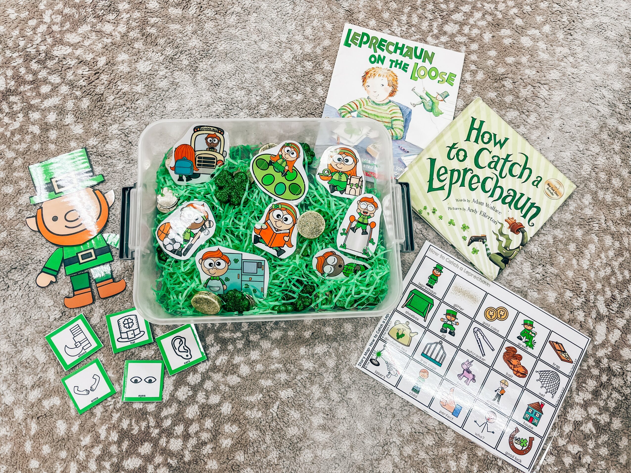 Leprechaun-themed game set with cards, stickers, and a box, on a textured surface, for children’s play and learning.