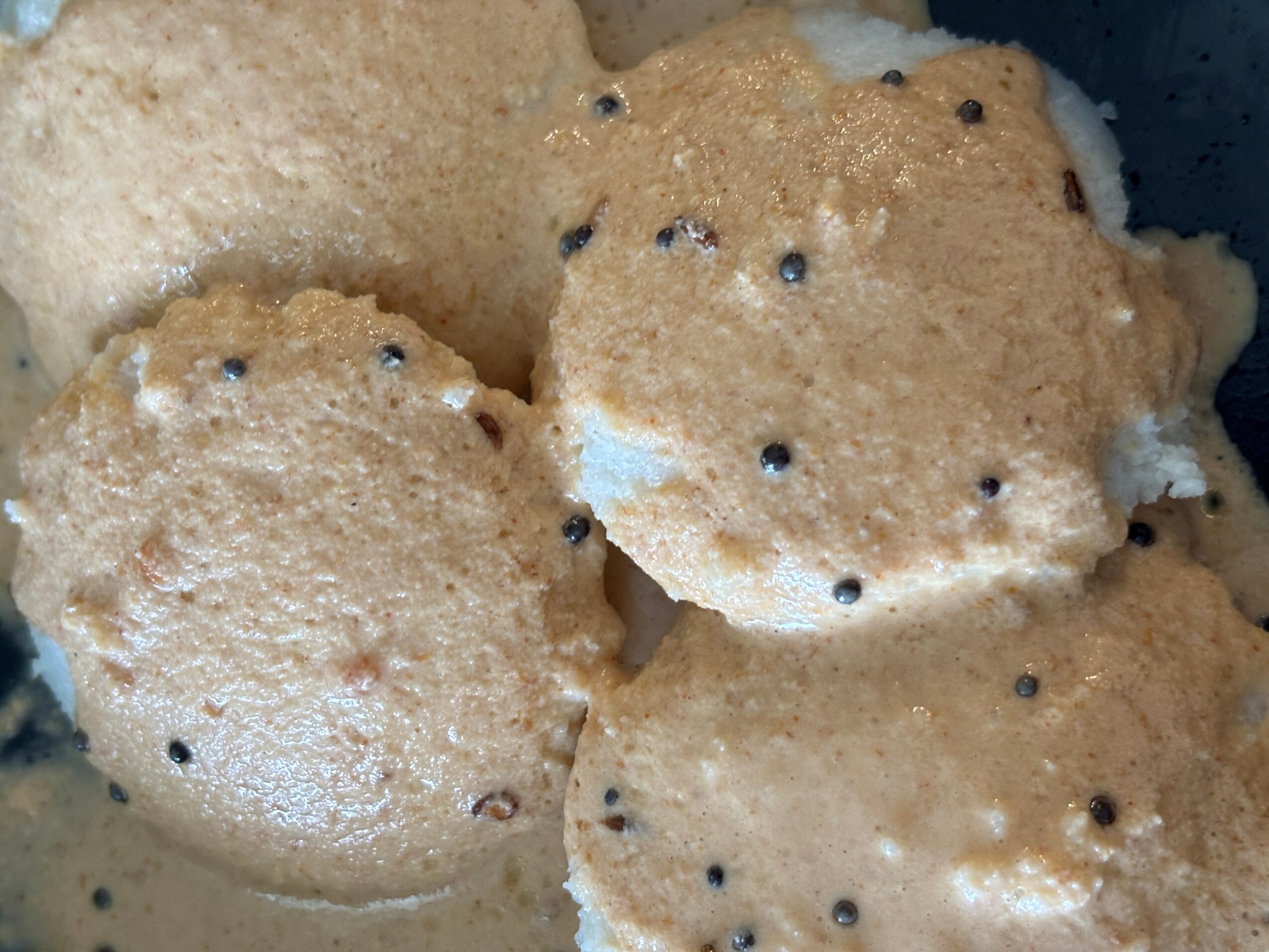 Close-up of round, golden-brown cookies with small black seeds on top.