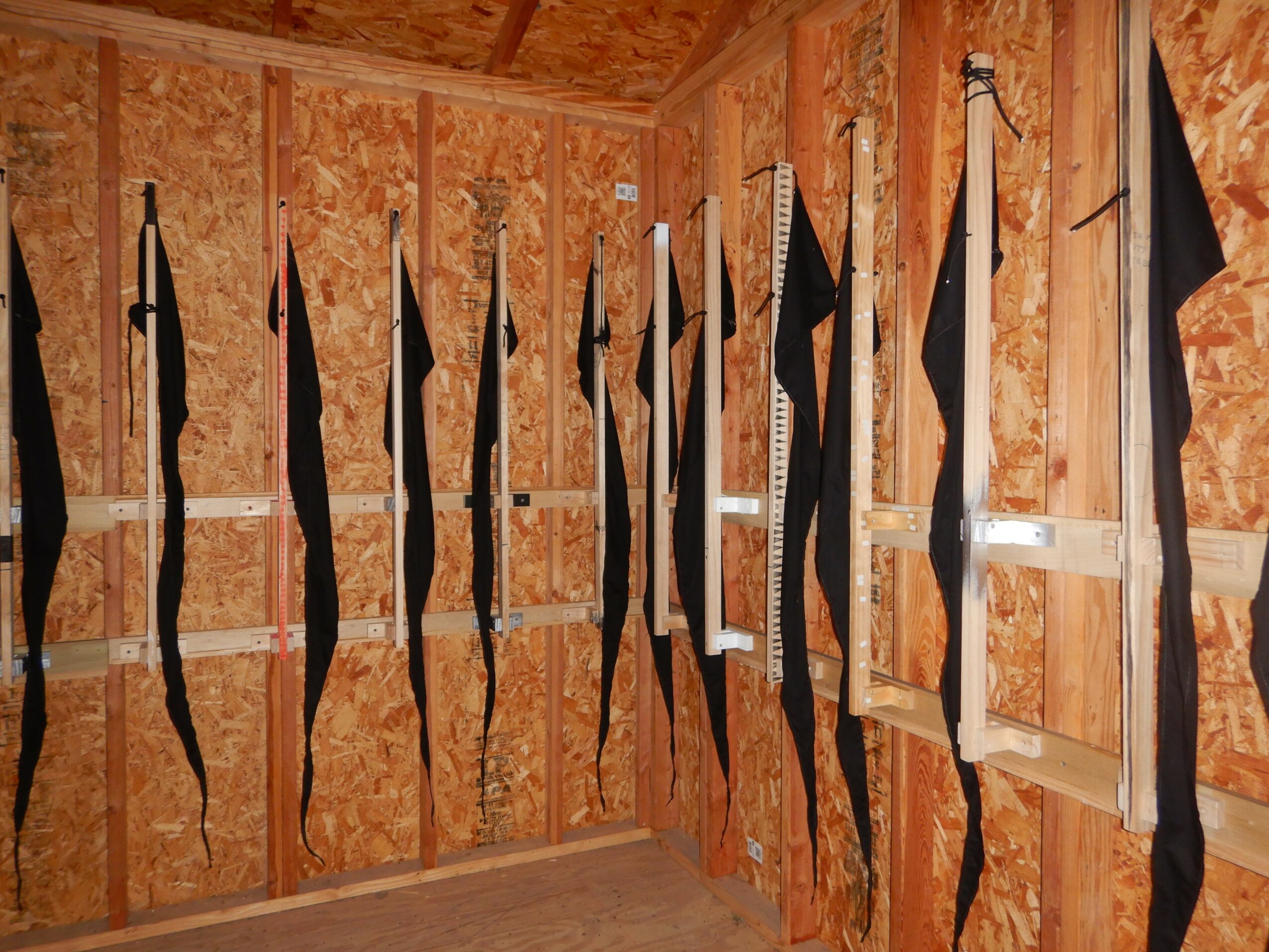 Black and white flags hanging vertically on a wooden wall inside a room, with a window on the right side.