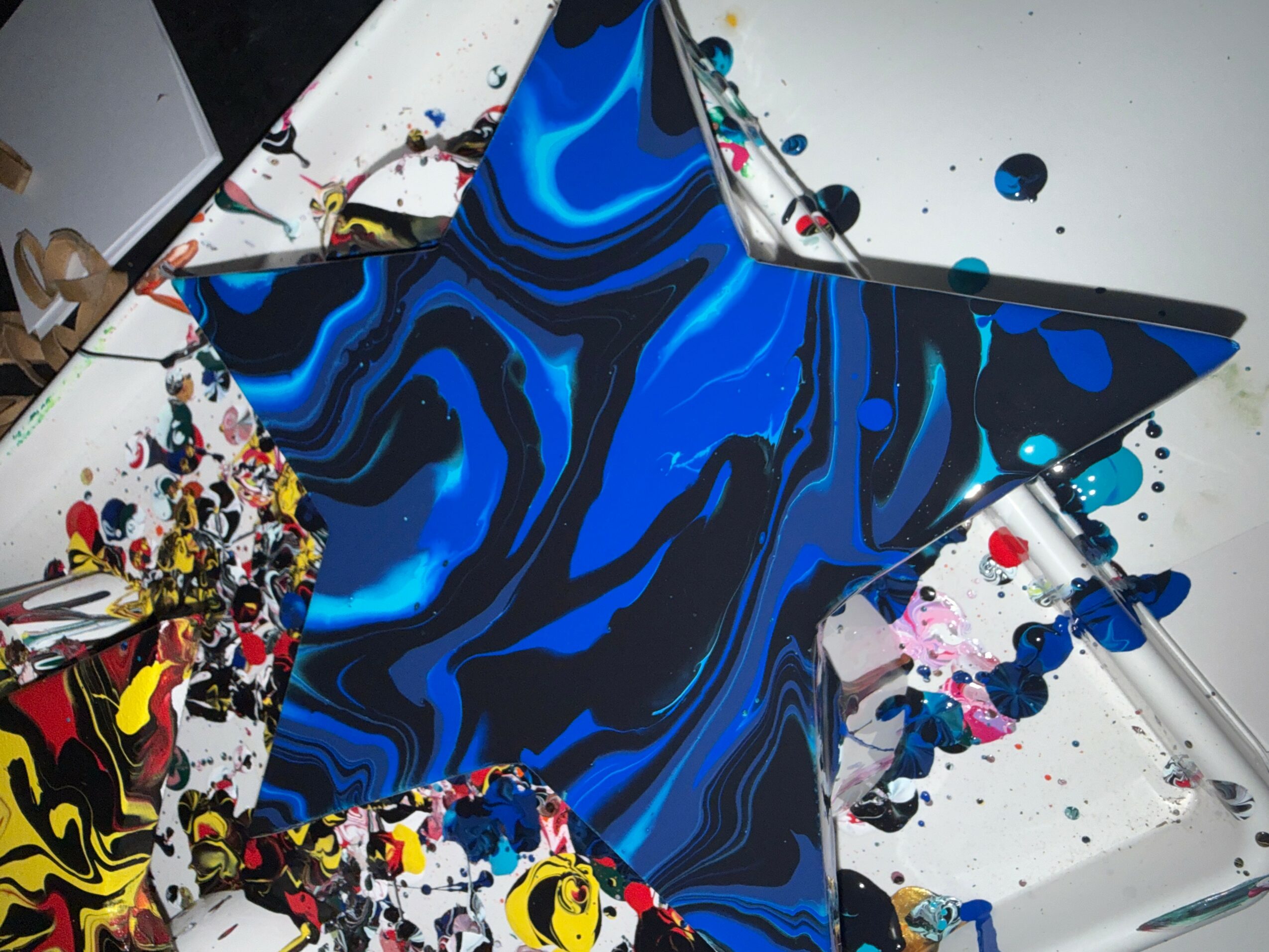 Blue and black marbled star sculpture on a table with colorful paint splatters.