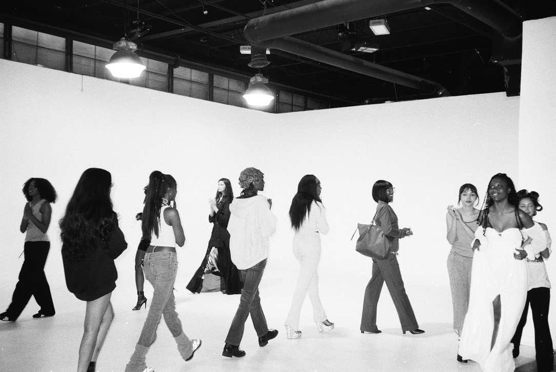 Group of people walking in a line inside a spacious, well-lit indoor space with high ceilings and hanging lights.