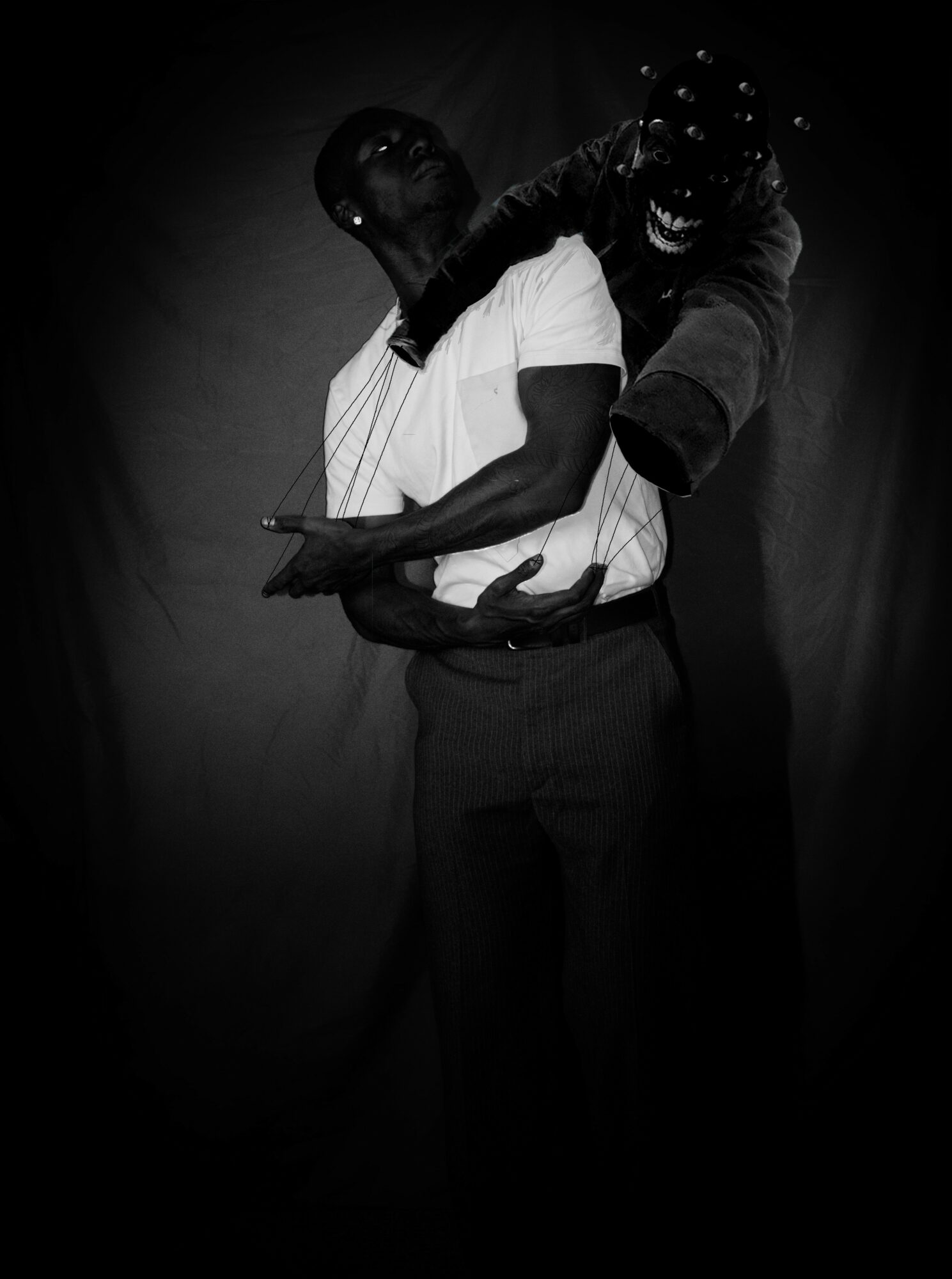 Two people embrace, one with glasses and curly hair, the other with short hair, in a dark setting.