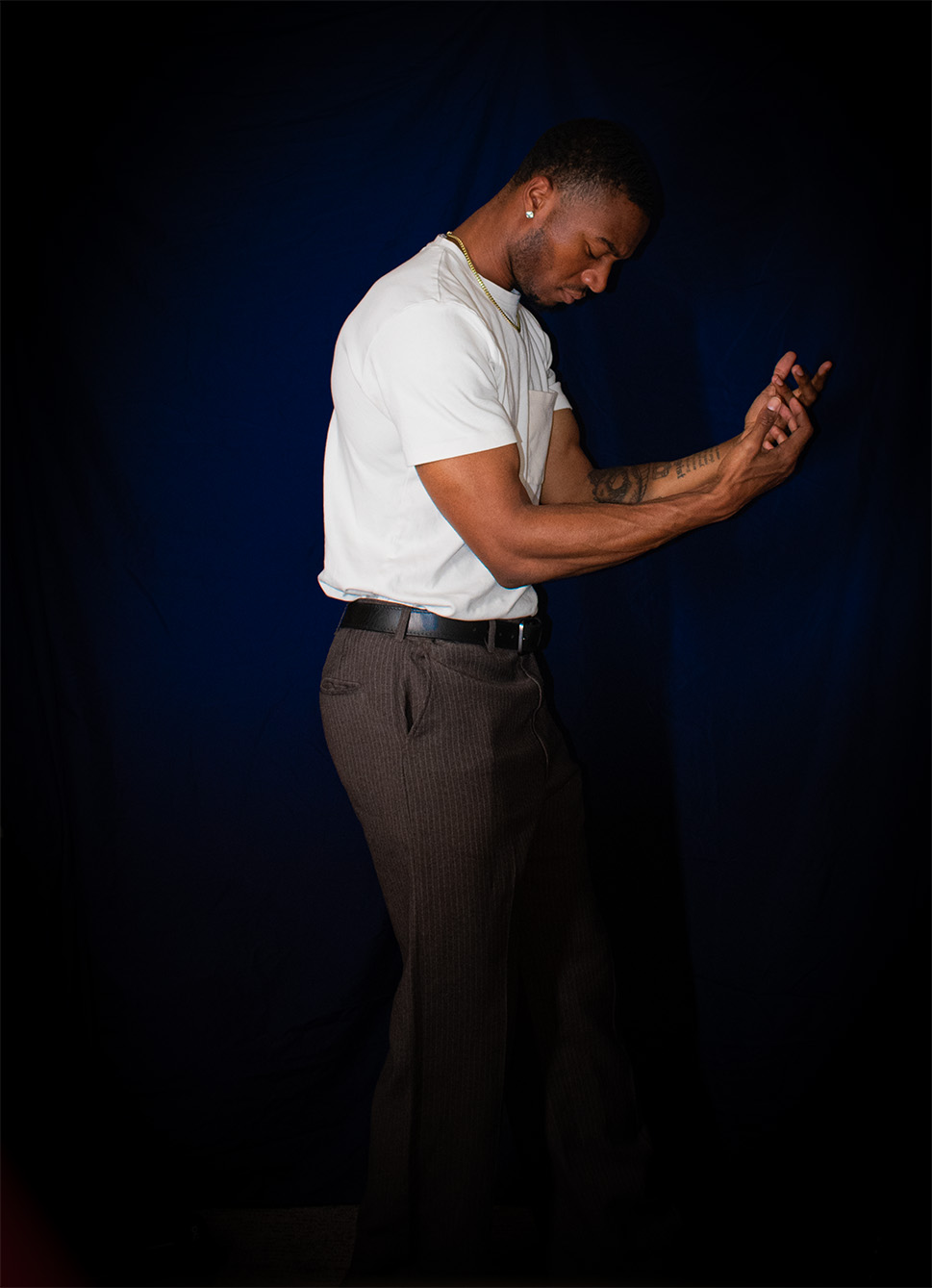 Man in white shirt and dark pants looking down and using a smartphone, dark background