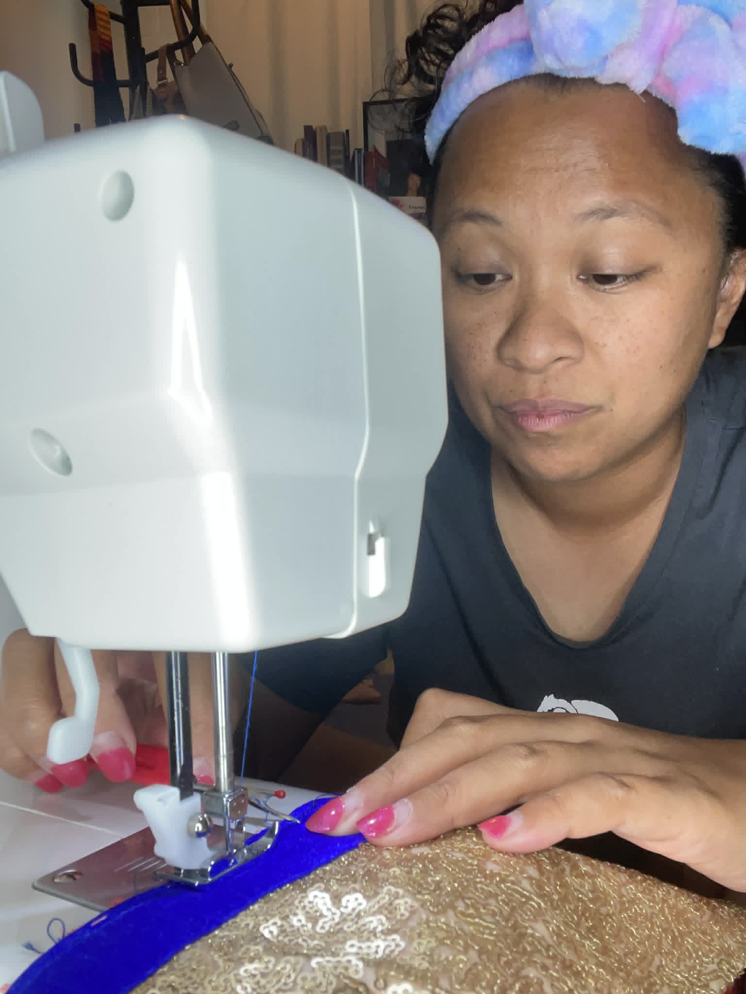 Woman with a colorful headband sewing fabric with a sewing machine, focusing on her work.