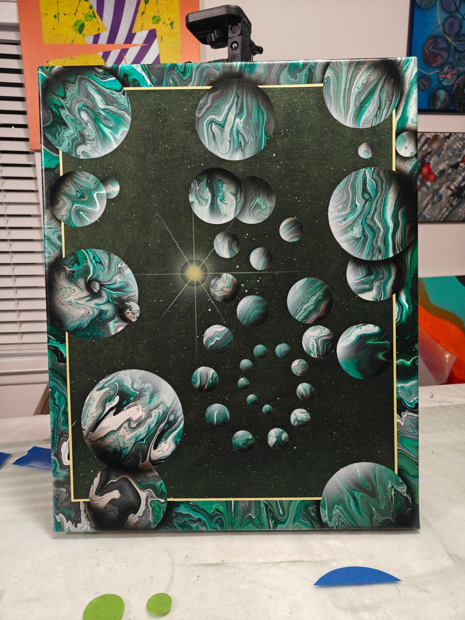 A framed artwork depicts planets and moons in space with a star at the center, surrounded by a decorative border.