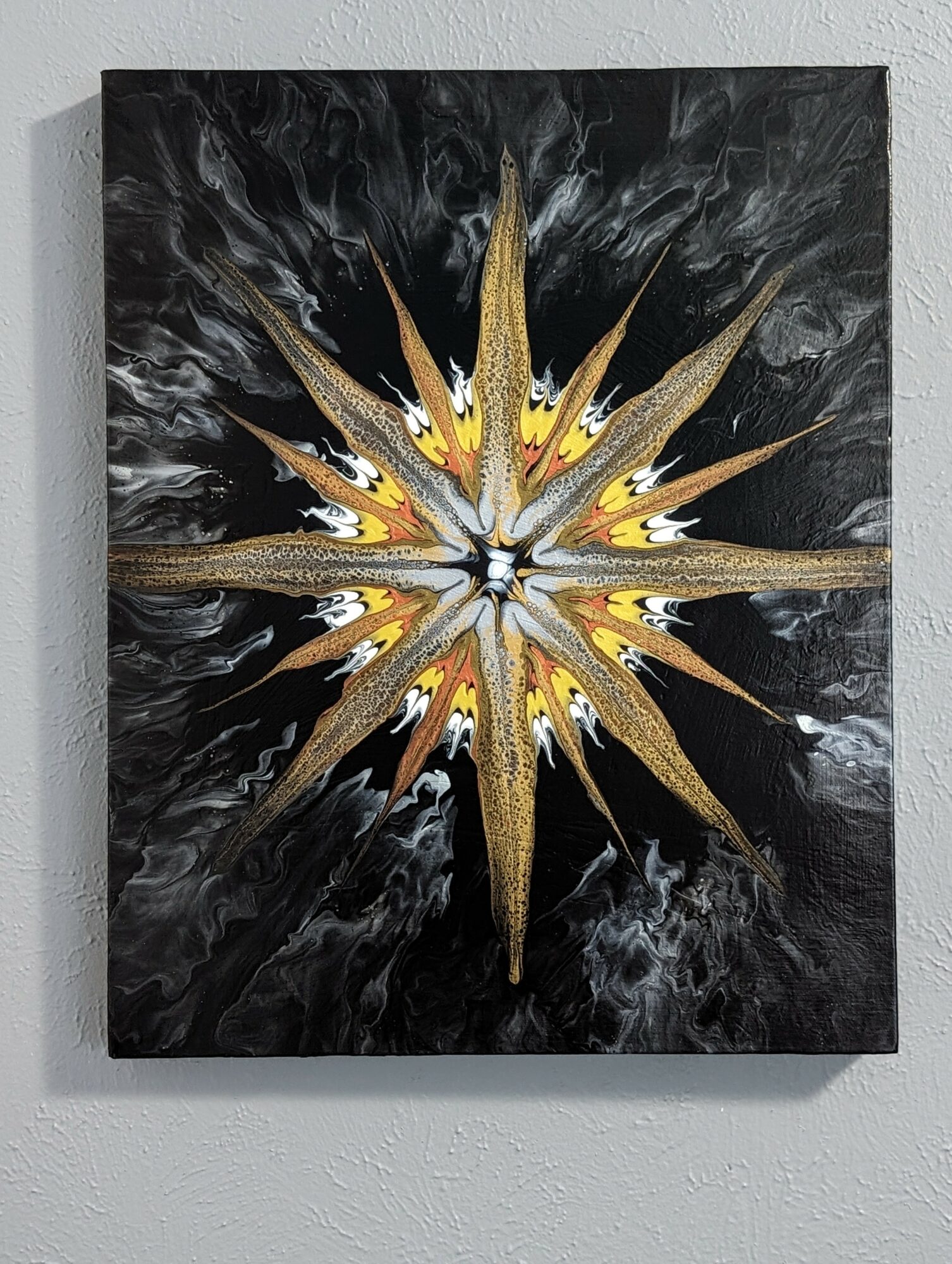 Abstract painting with a starburst pattern in gold, white, and black colors on a black background.
