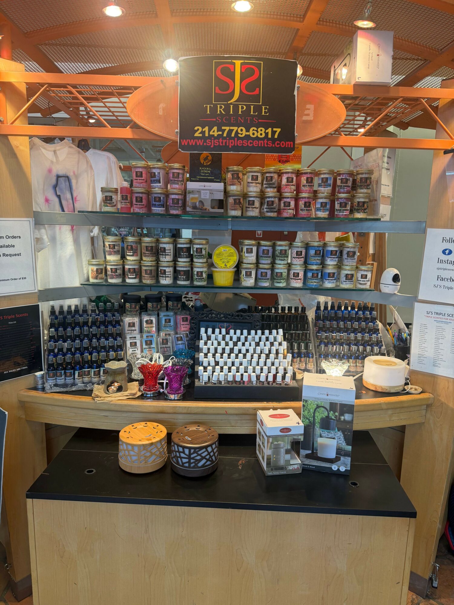 Display of various small bottles and containers on a black table with shelves of products behind, in a store.