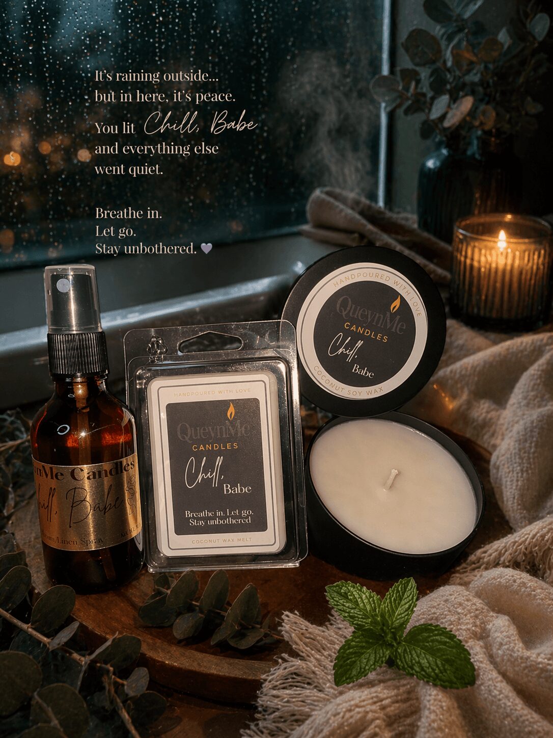 Candles, a spray bottle, and a plant on a table with a quote on the wall in the background.