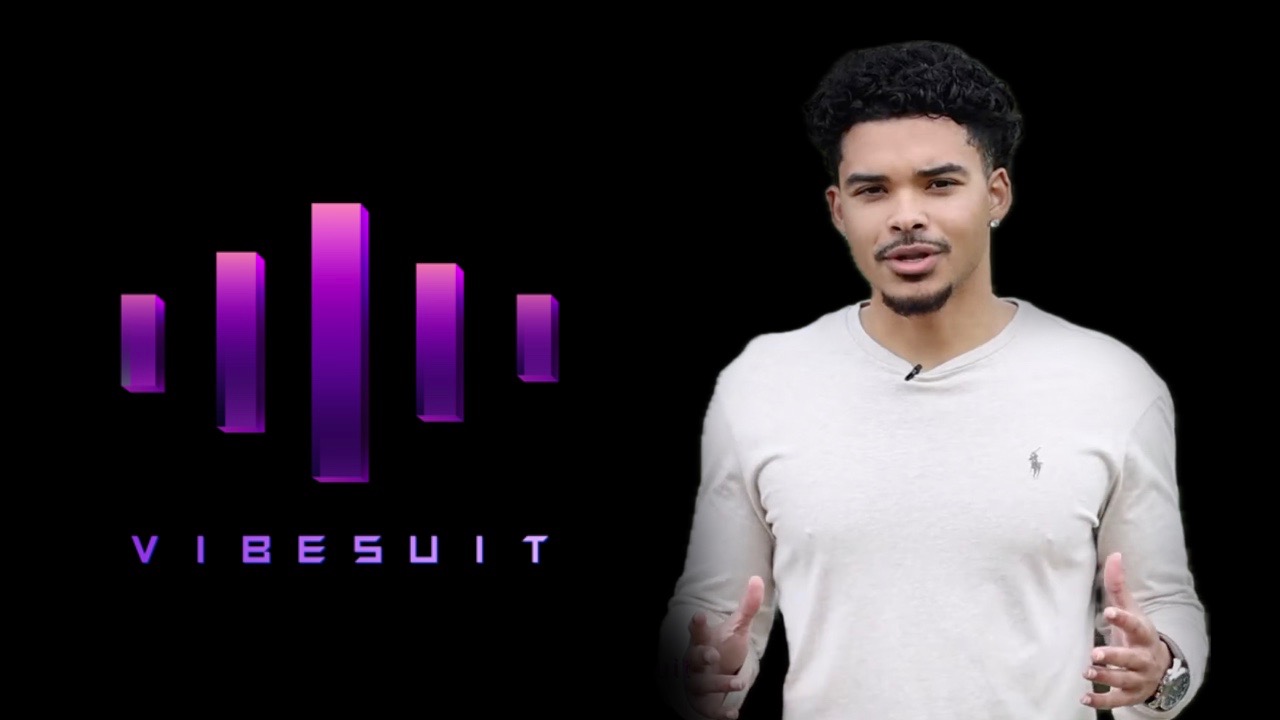 A young man with curly hair and a white shirt standing next to a logo with purple vertical bars and the text 'VIBESUIT'.