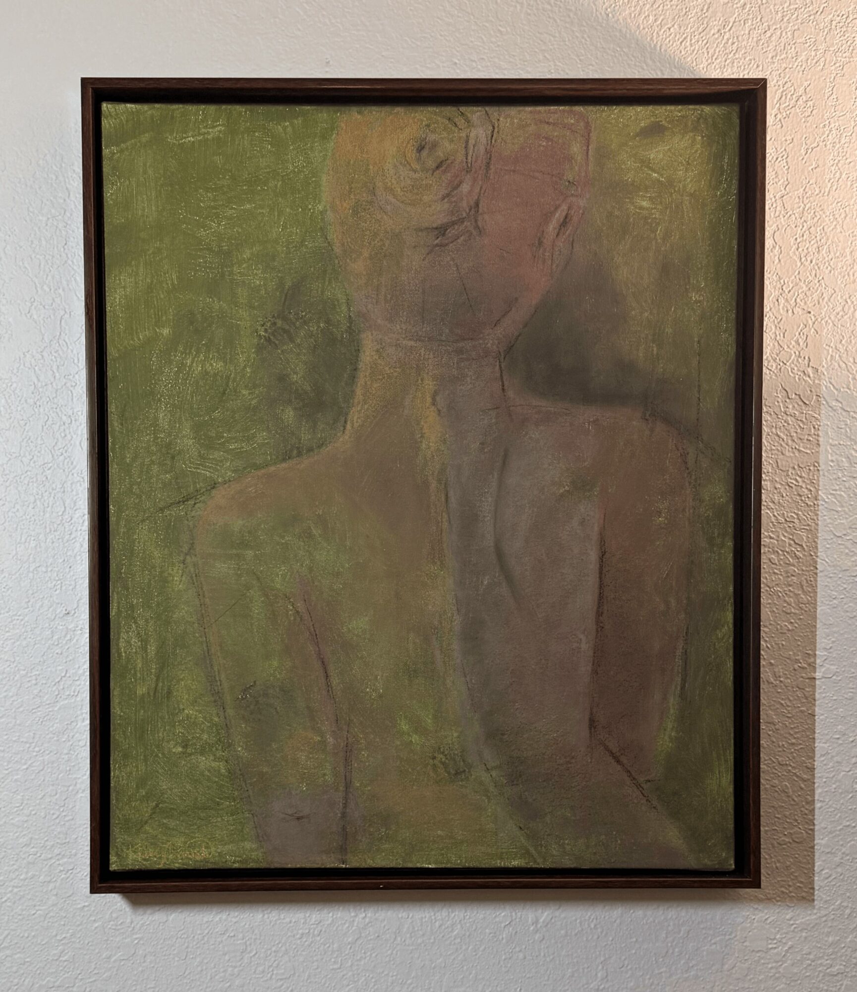 Framed abstract painting with green, purple, and gray colors on a white wall.