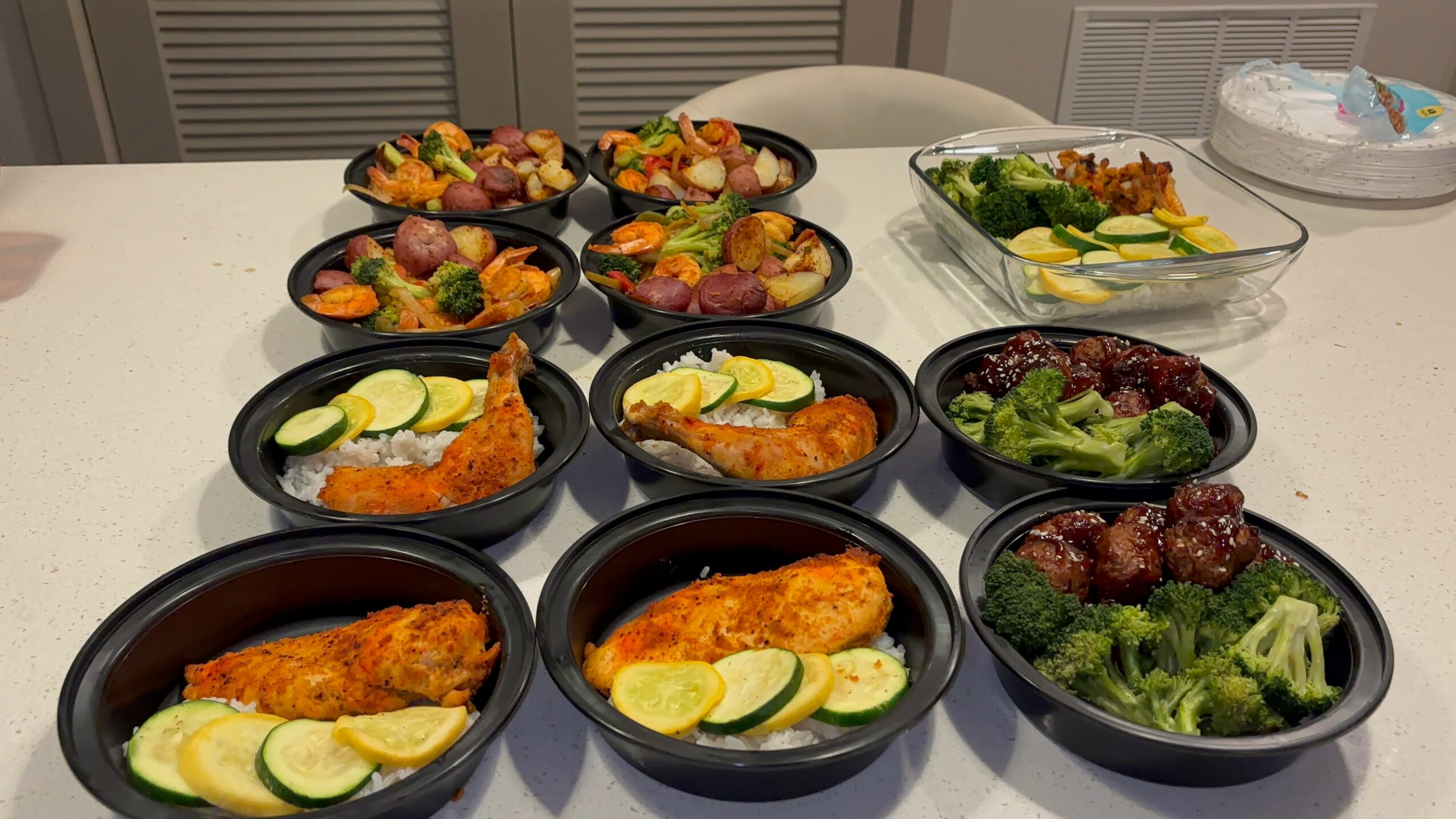 Assorted dishes including fried fish, vegetables, and salads on a table, with some plates containing lemon slices and broccoli.