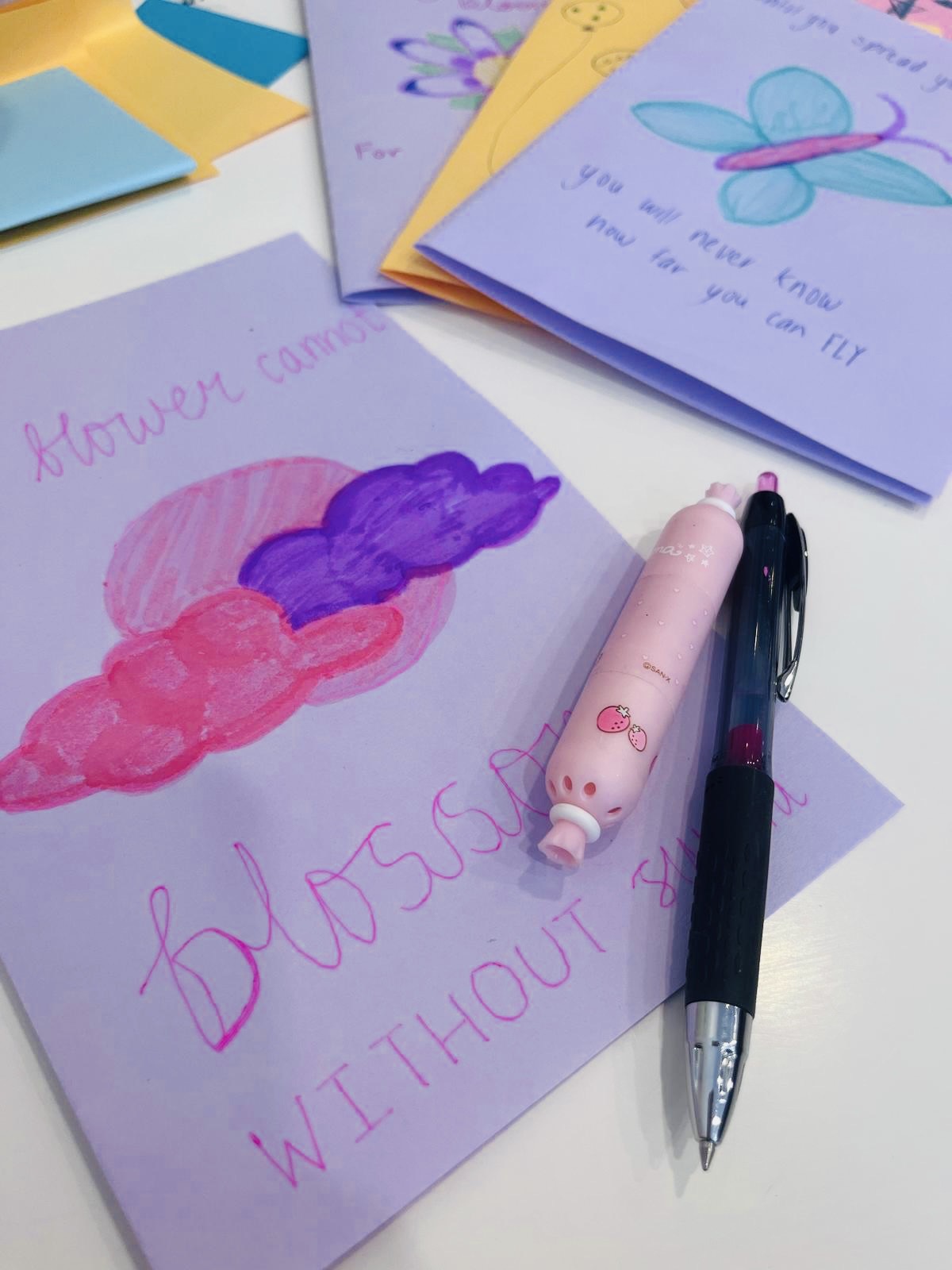 Colorful handwritten notes and drawings on paper, with pens and a pink highlighter on a white surface.