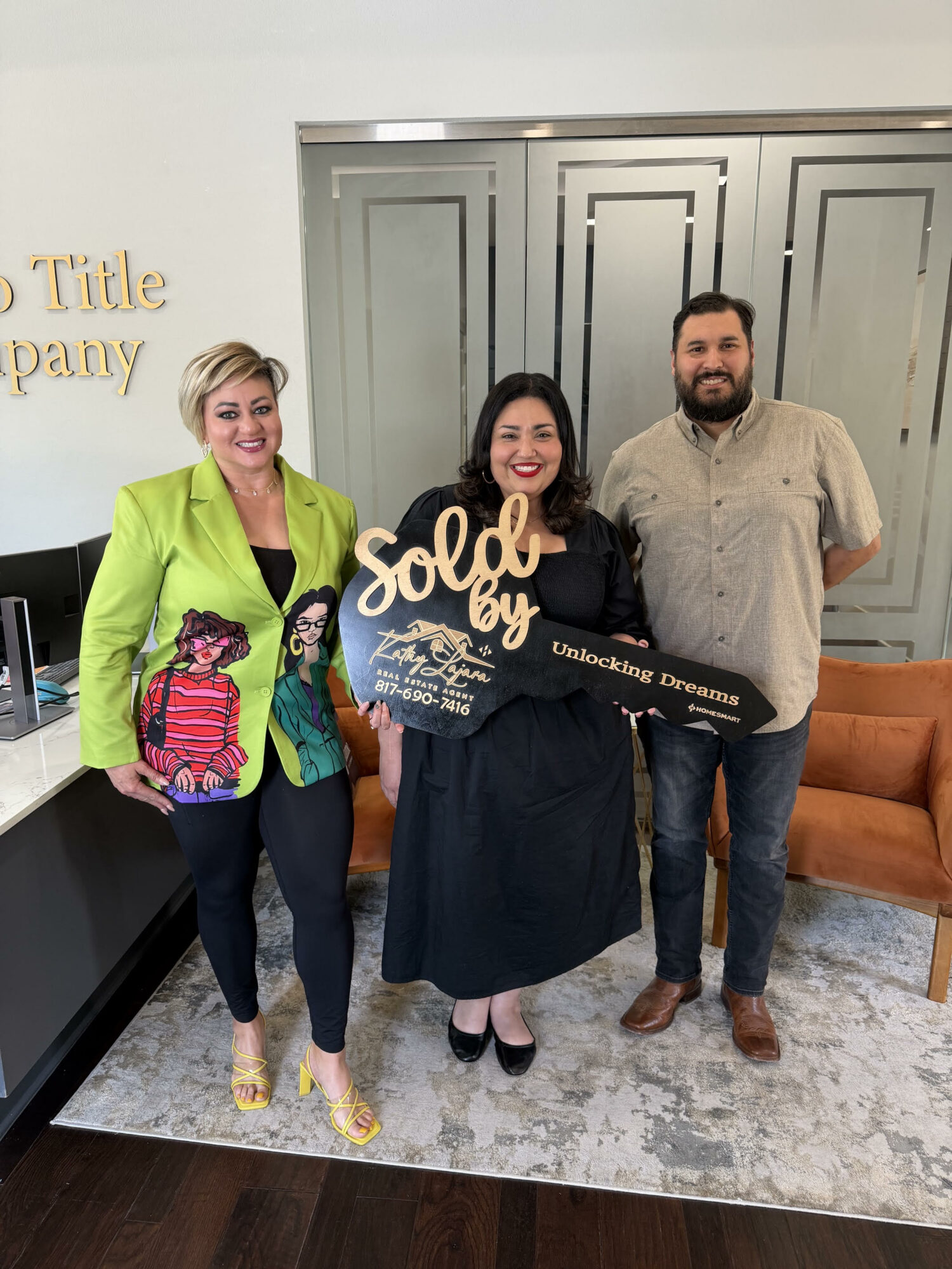 Three people standing indoors, one holding a sign that says