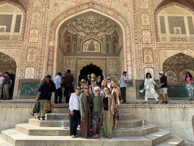 Group of people standing on steps in front of an ornate, decorated building entrance with intricate patterns and arches.