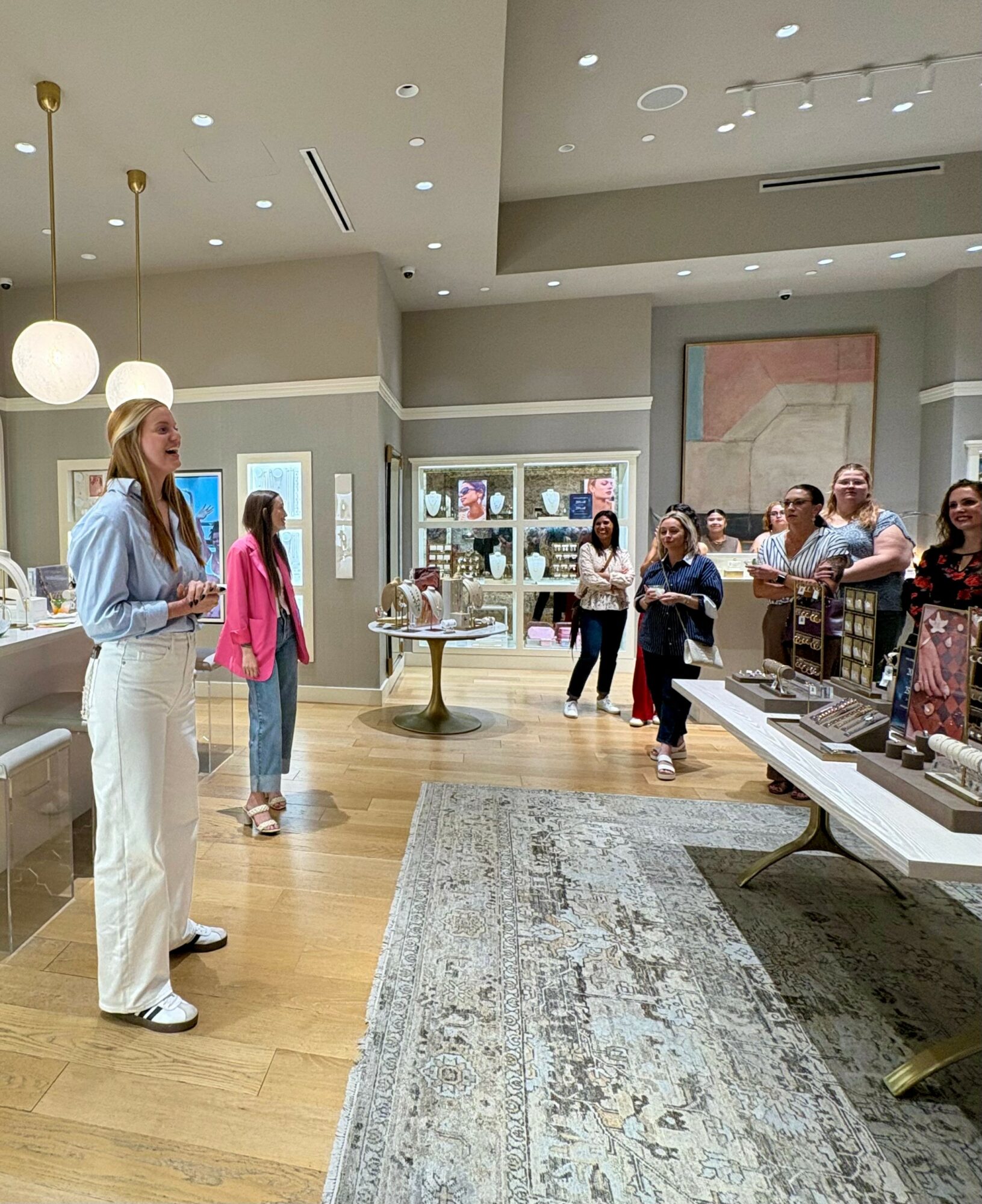 Group of people inside a retail store, some looking at displays, others talking, with shelves and artwork in the background.