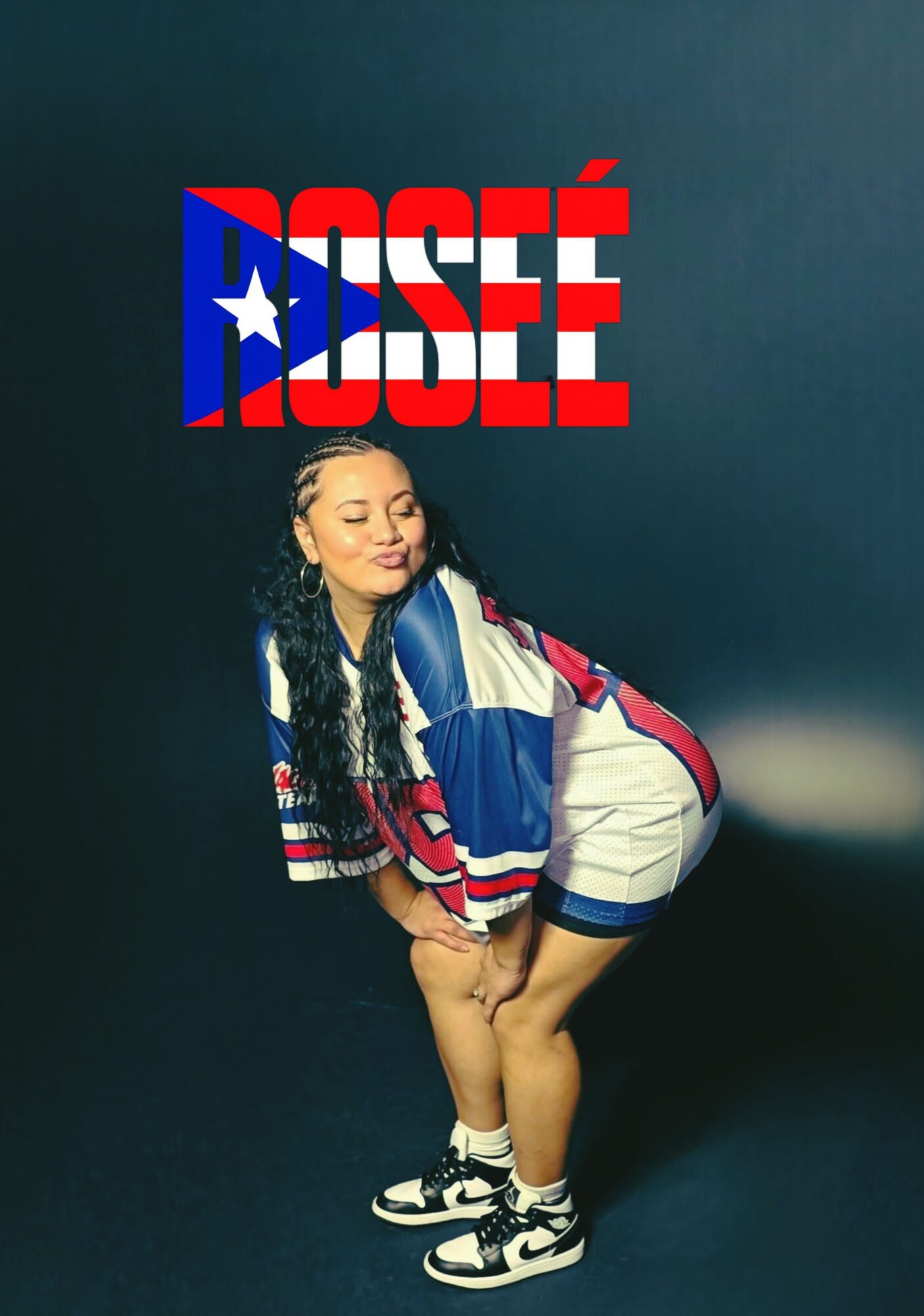 Young woman with long curly hair poses in front of a dark background with a logo reading 'ROSΓ' in red, white, and blue colors.