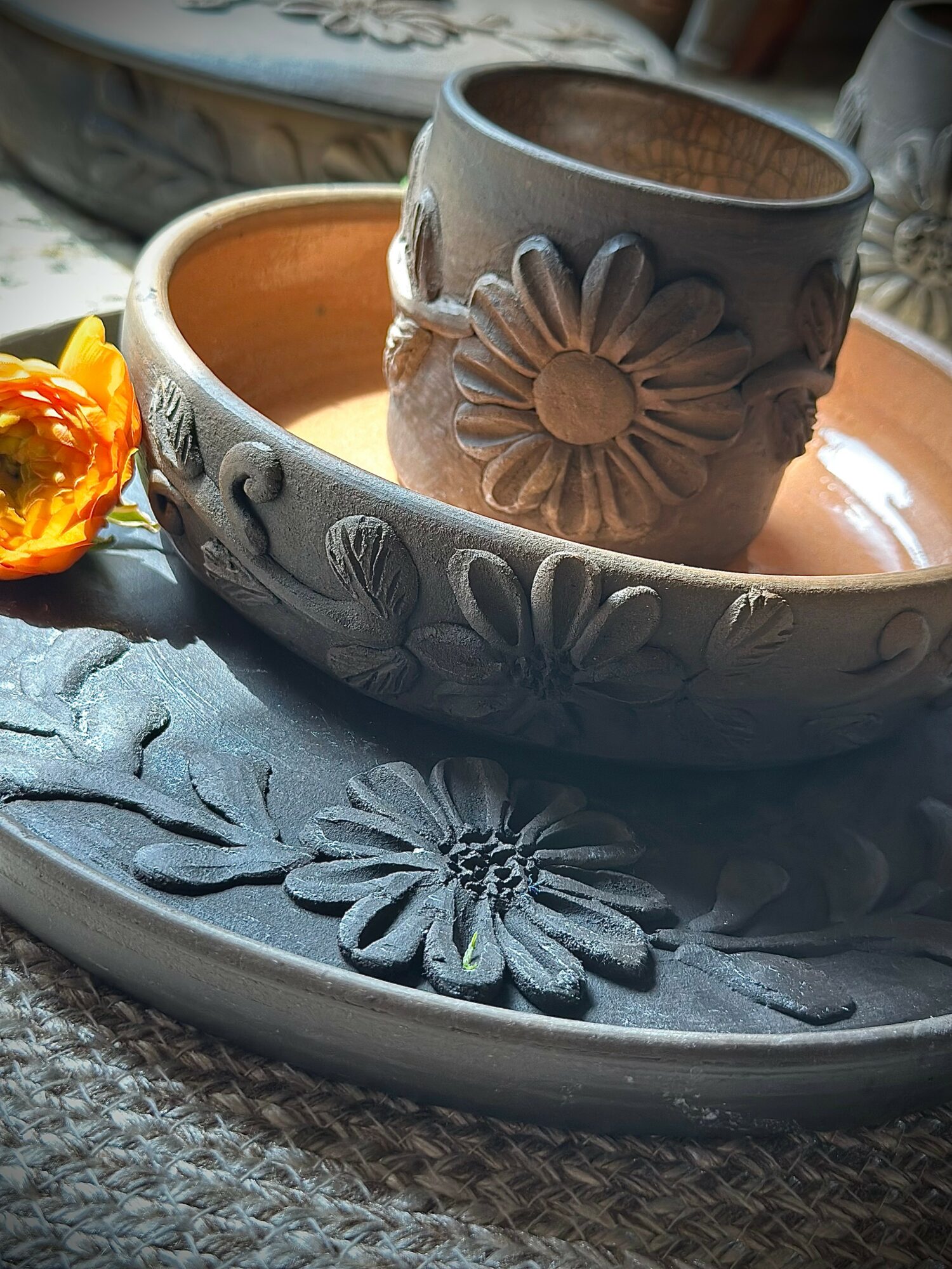 Decorative ceramic flower-shaped container with a daisy design, placed inside a larger bowl with similar floral patterns, on a textured surface.