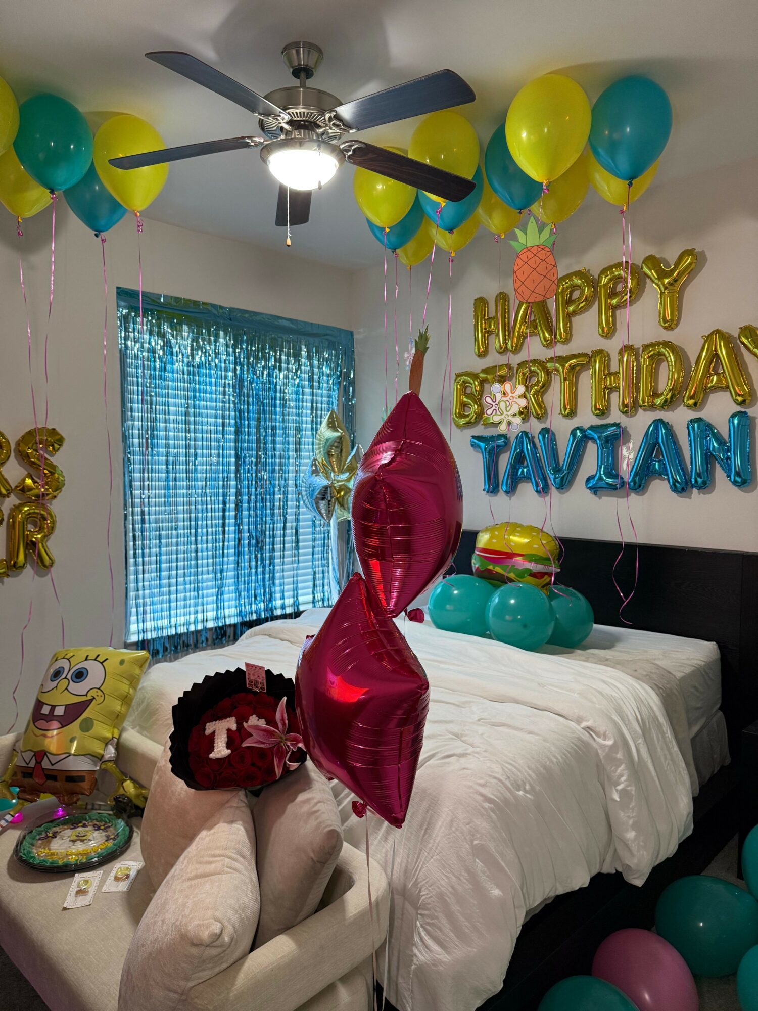Room decorated for a birthday with balloons, a cake, and a