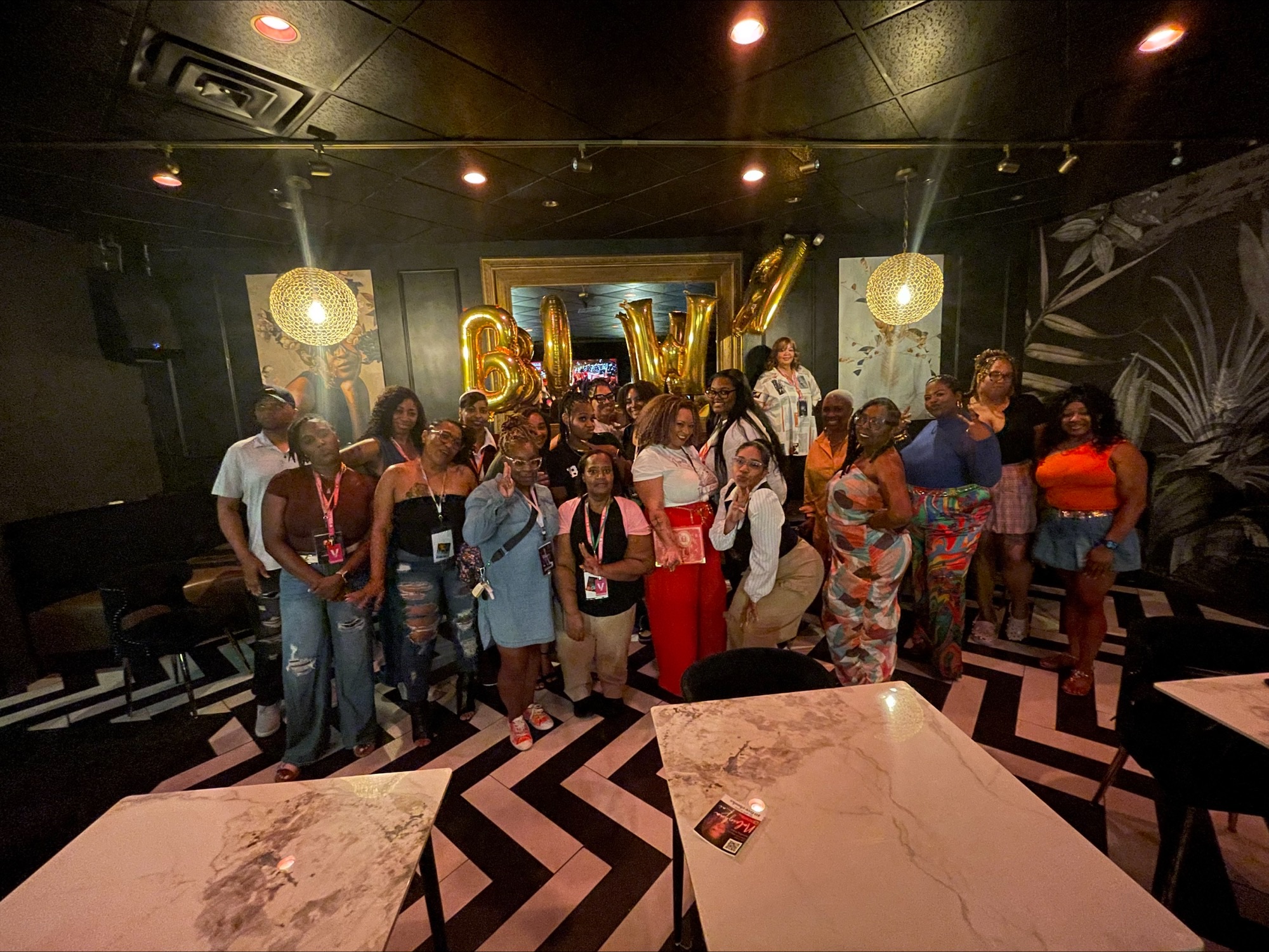 Group of people gathered in a dimly lit room with decorative lighting and a large gold