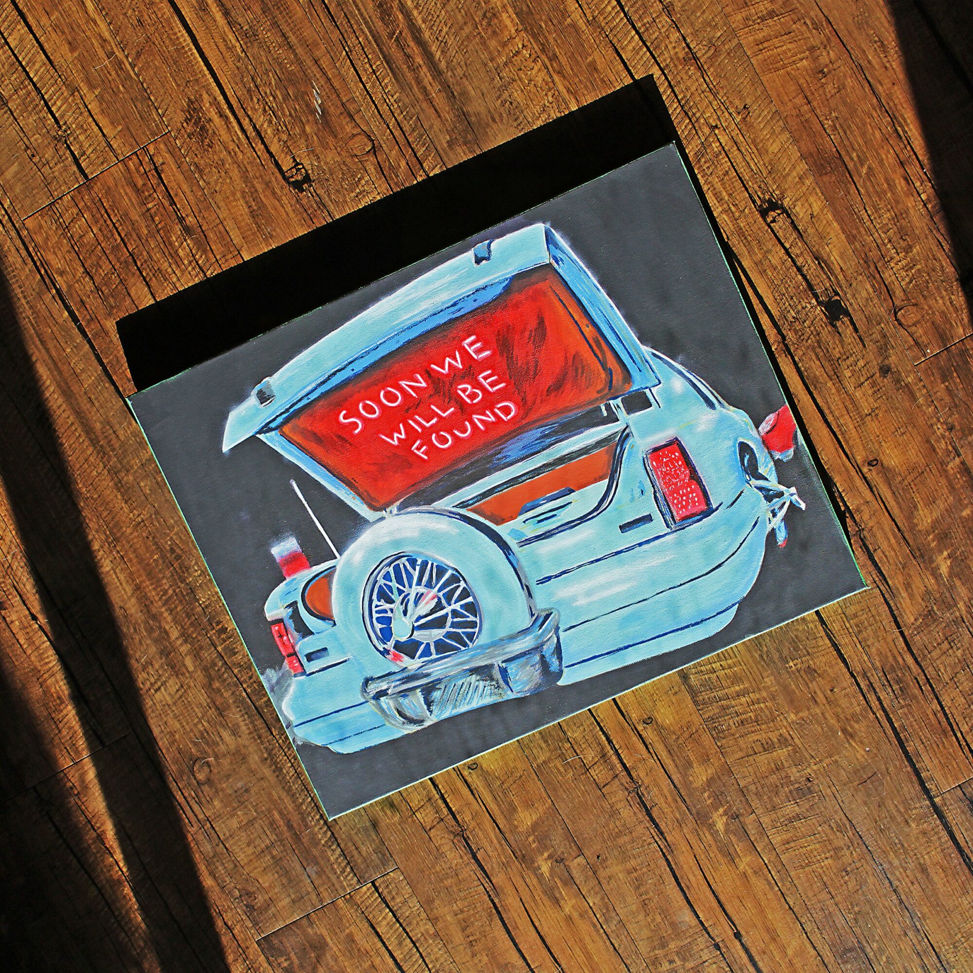 Painting of a car with an open trunk showing a red sign that reads 'Soon we will be found'.