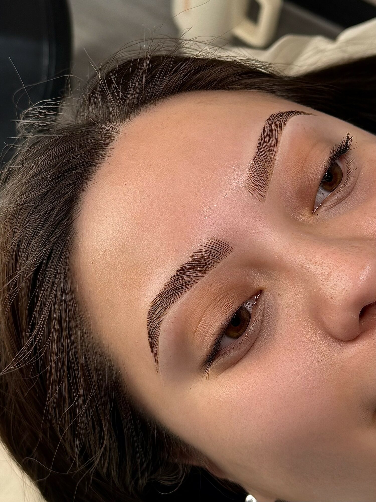 Close-up of a woman's face showing well-groomed eyebrows and partially visible eyes, with the image rotated 90 degrees clockwise.