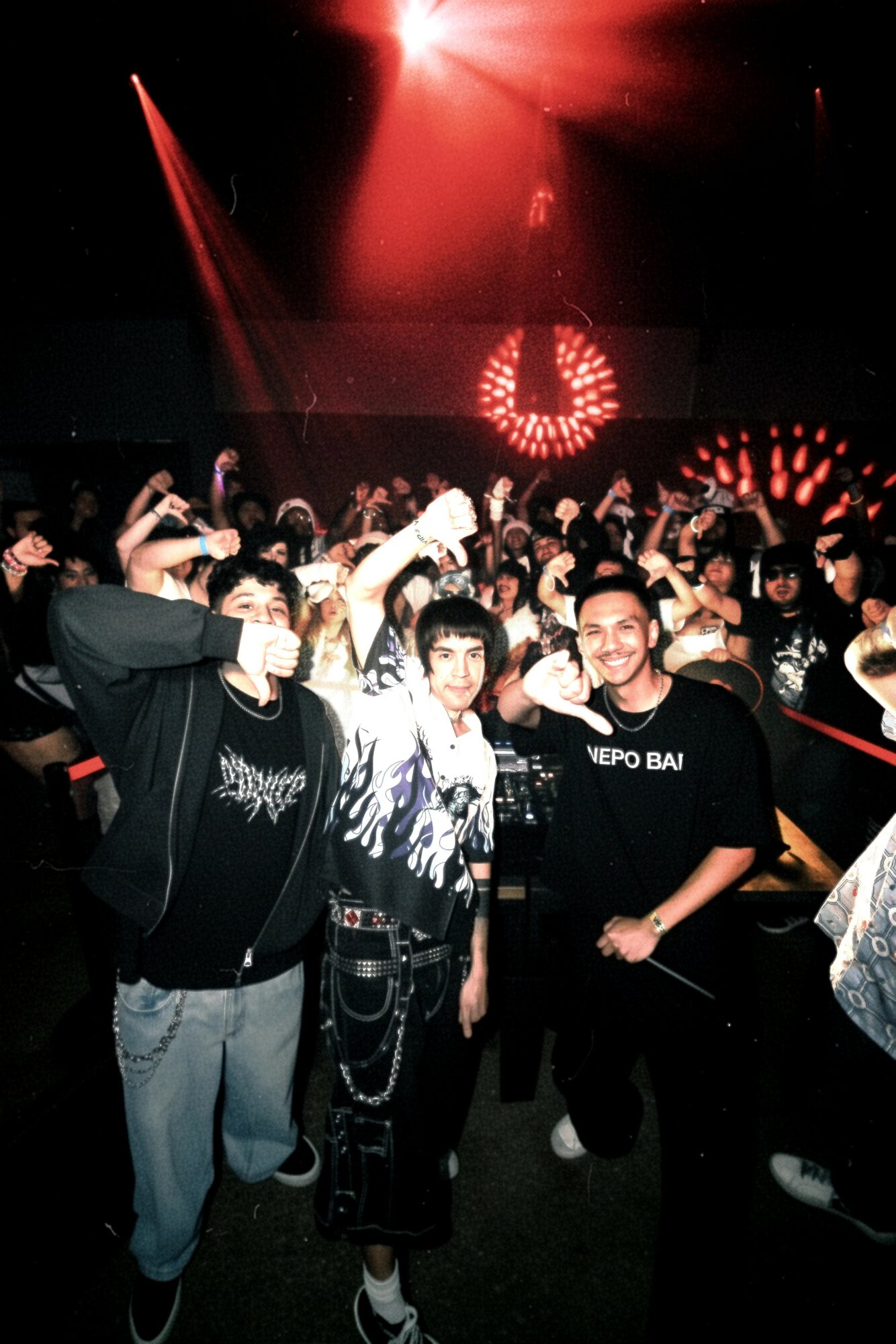 Group of people at a concert or event with stage lighting and a large illuminated number six in the background.