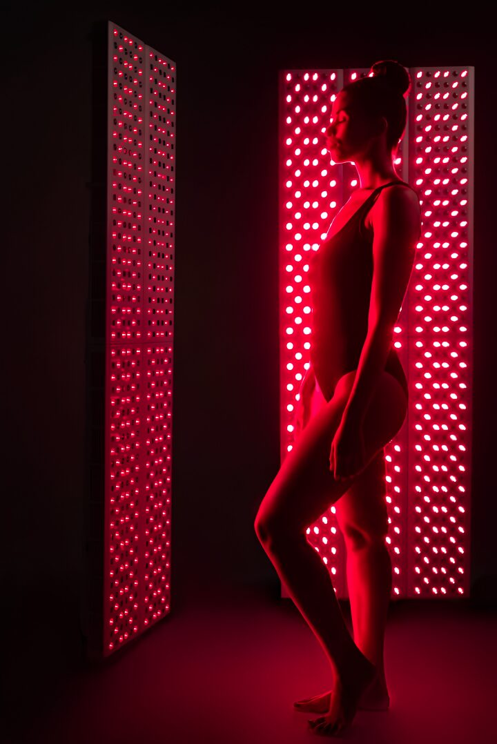 Silhouette of a woman standing between two illuminated pink LED panels in a dark room.