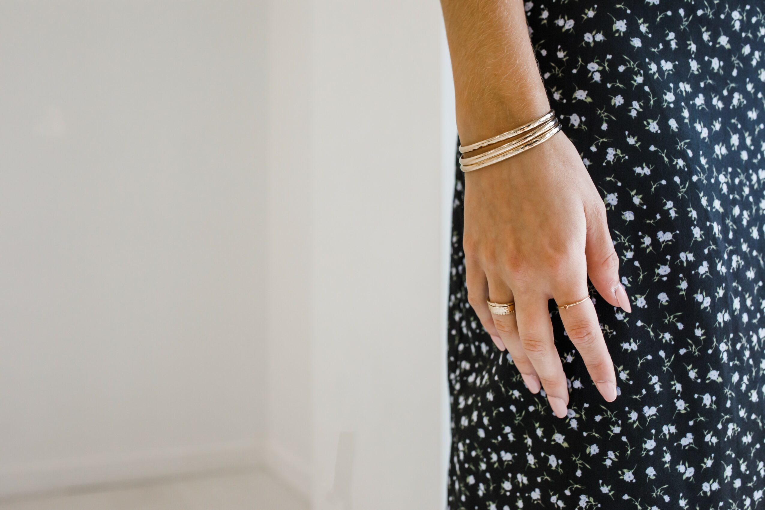Person's hand with rings and bracelets resting on their black and white patterned dress.