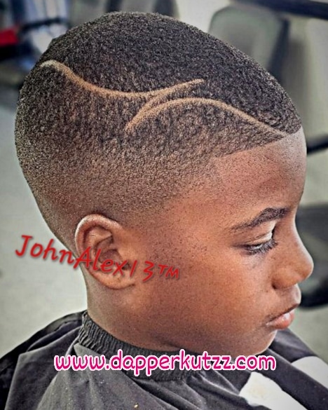 Side profile of a young boy with a short, textured haircut and decorative lines shaved into his hair.