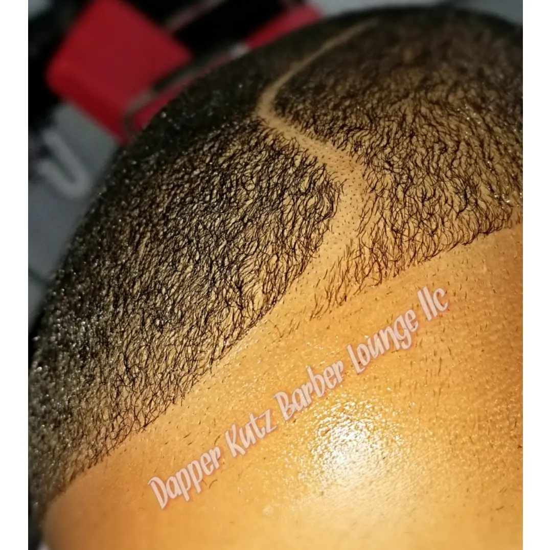 Close-up of a person's haircut with a fade and a design shaved into the side, with text overlay. Word count: 20