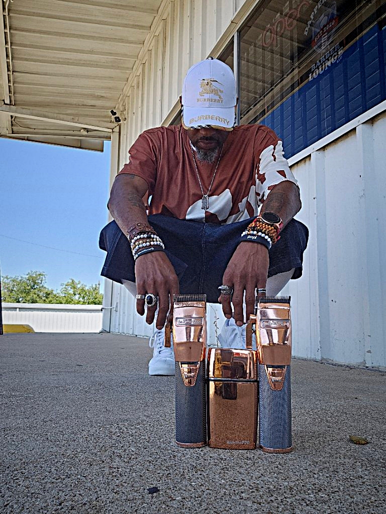 Person crouching outdoors with a hat, wearing a red shirt, surrounded by glasses and bottles on the ground.