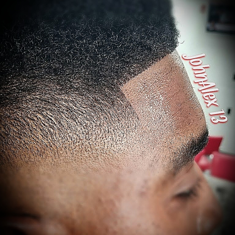 Close-up of a person's hairstyle with a fade, showing textured hair on top and a clean shaved line on the side.