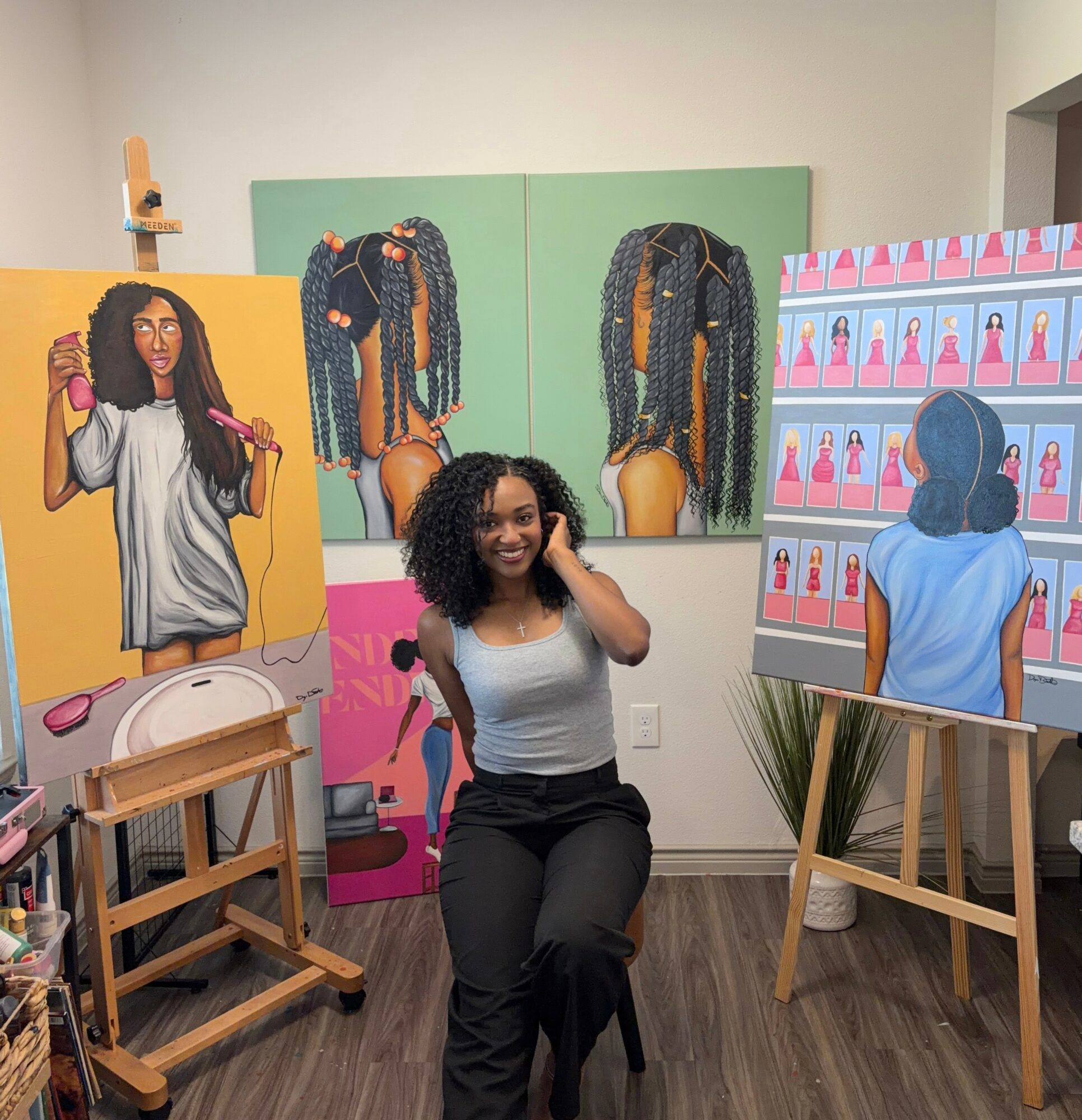 Seated woman with curly hair in front of colorful paintings of women with braided hair and a woman shopping for products. Word count: 20