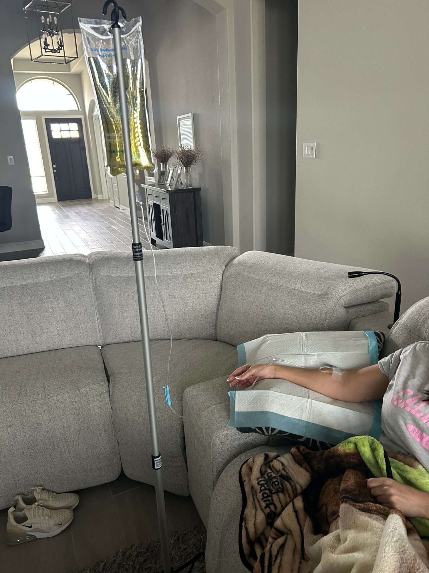 Living room with a gray sofa, a window, and various items on the sofa and floor.