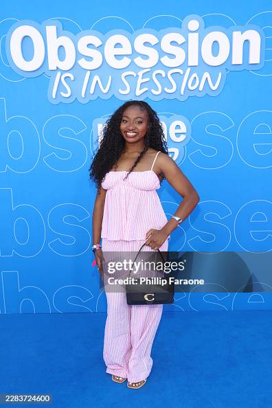 Woman in pink and white striped outfit smiling in front of blue background with text
