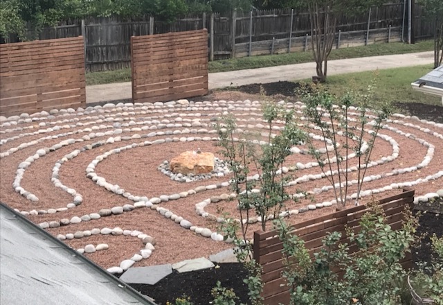 Garden with circular rock patterns, small trees, and wooden fences, viewed from above.
