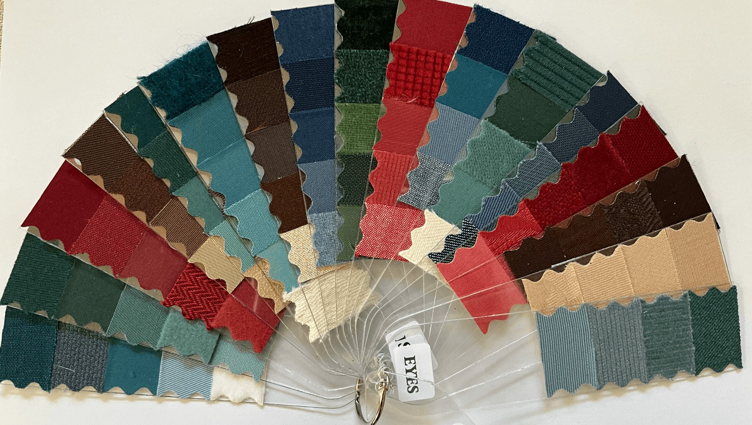 Fan-shaped display of fabric swatches in various colors, arranged in a semi-circle on a white background.