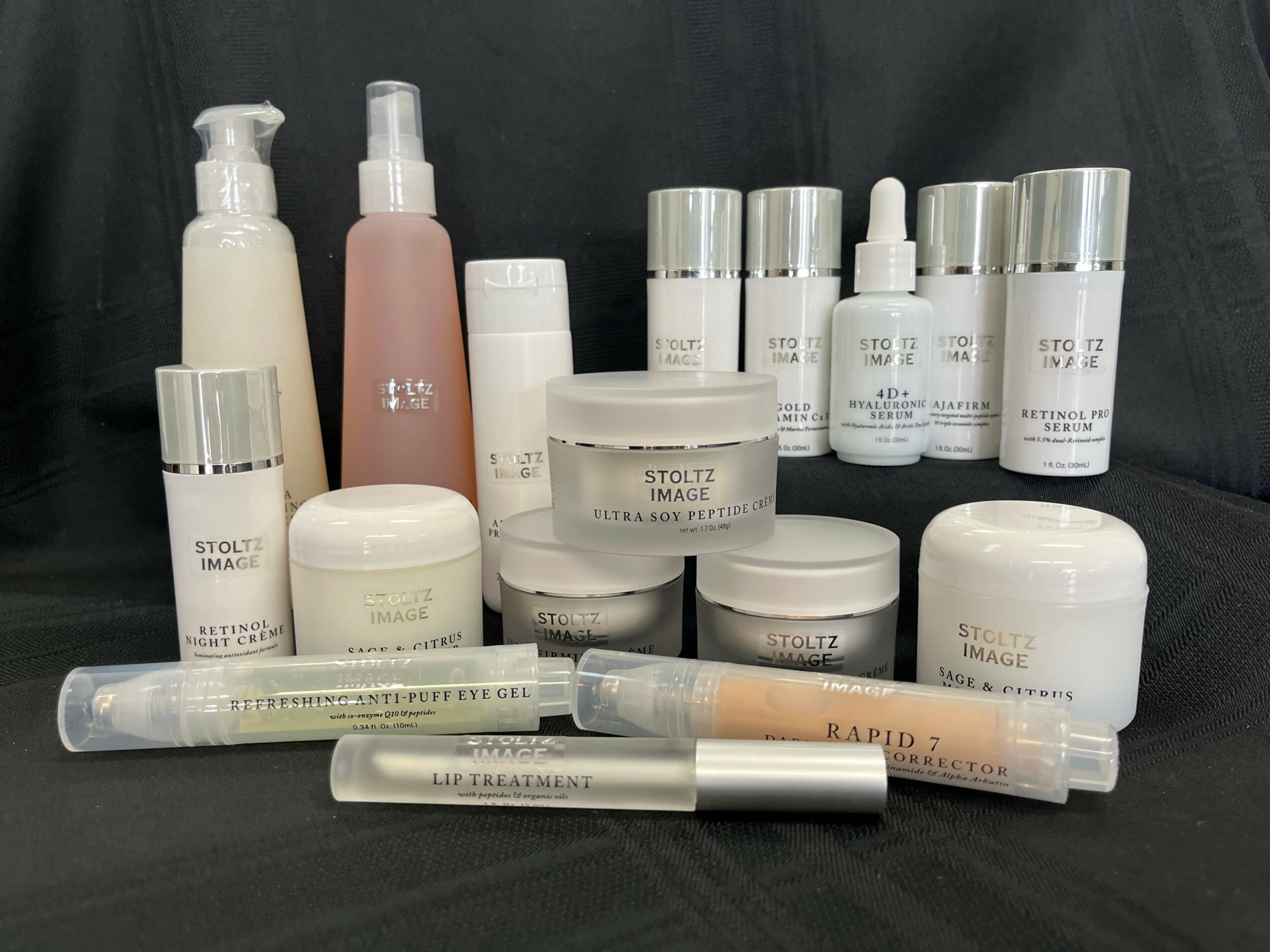Collection of skincare and cosmetic products including bottles, jars, and tubes on a black background.