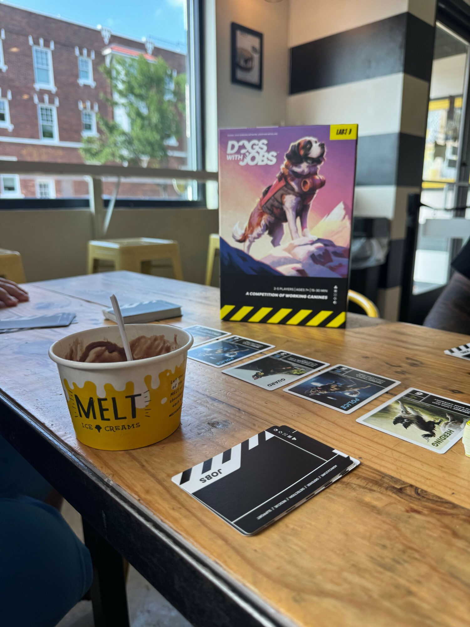 Table with popcorn bucket, promotional materials, and a poster in the background, inside a room with windows and a view outside.